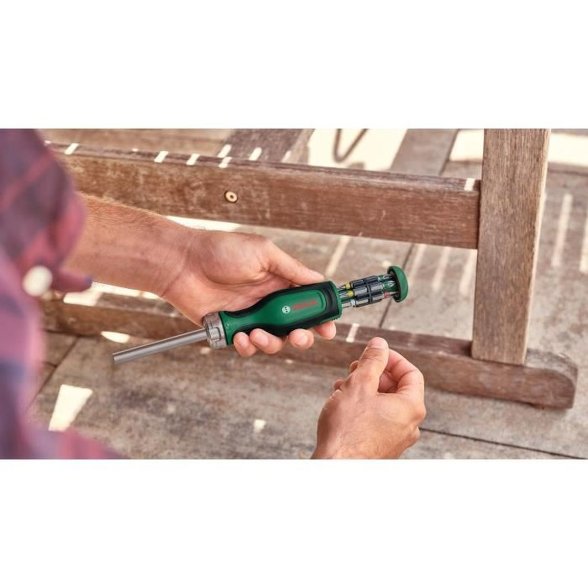Cacciavite verde con punte tenuto da mani, mobili in legno sullo sfondo.