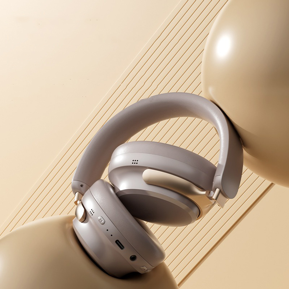 Auriculares grises con detalles dorados sobre fondo beige.