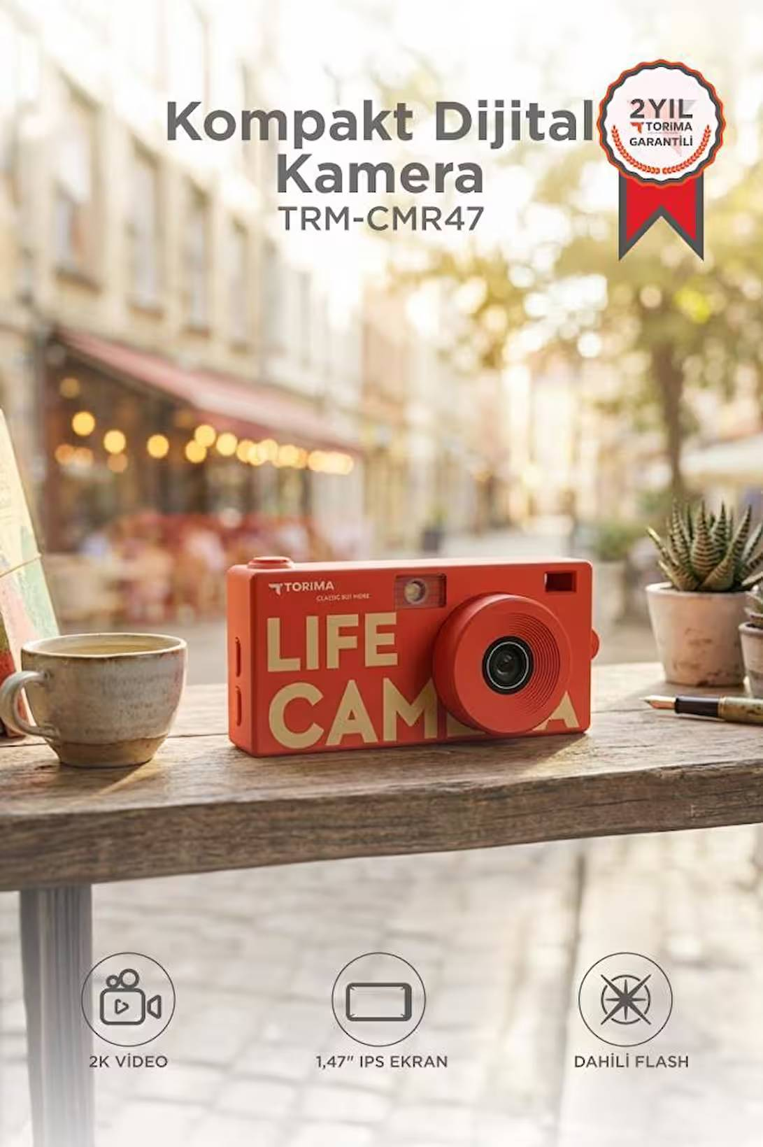 Ahşap masa üzerinde fincanın yanında "LIFE CAM" yazılı kırmızı dijital kamera.