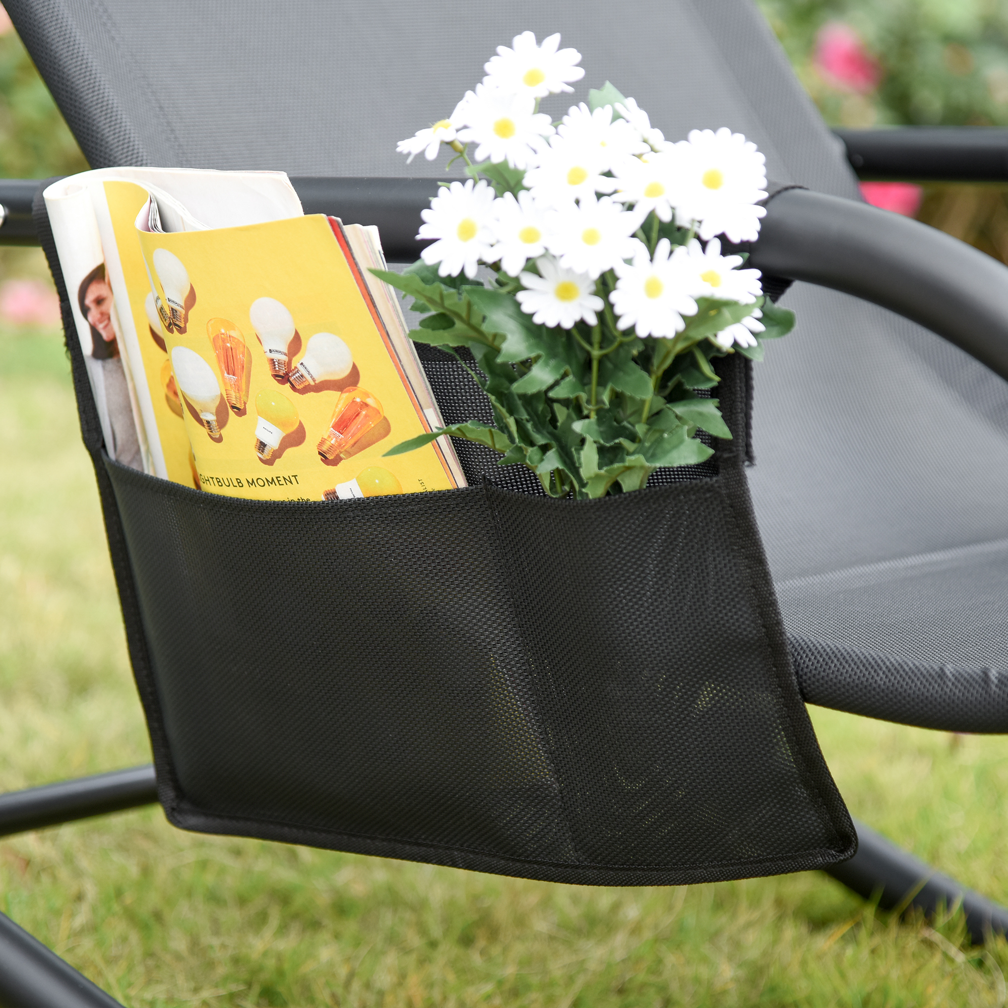 Un organizador negro en una silla gris con libros y flores.