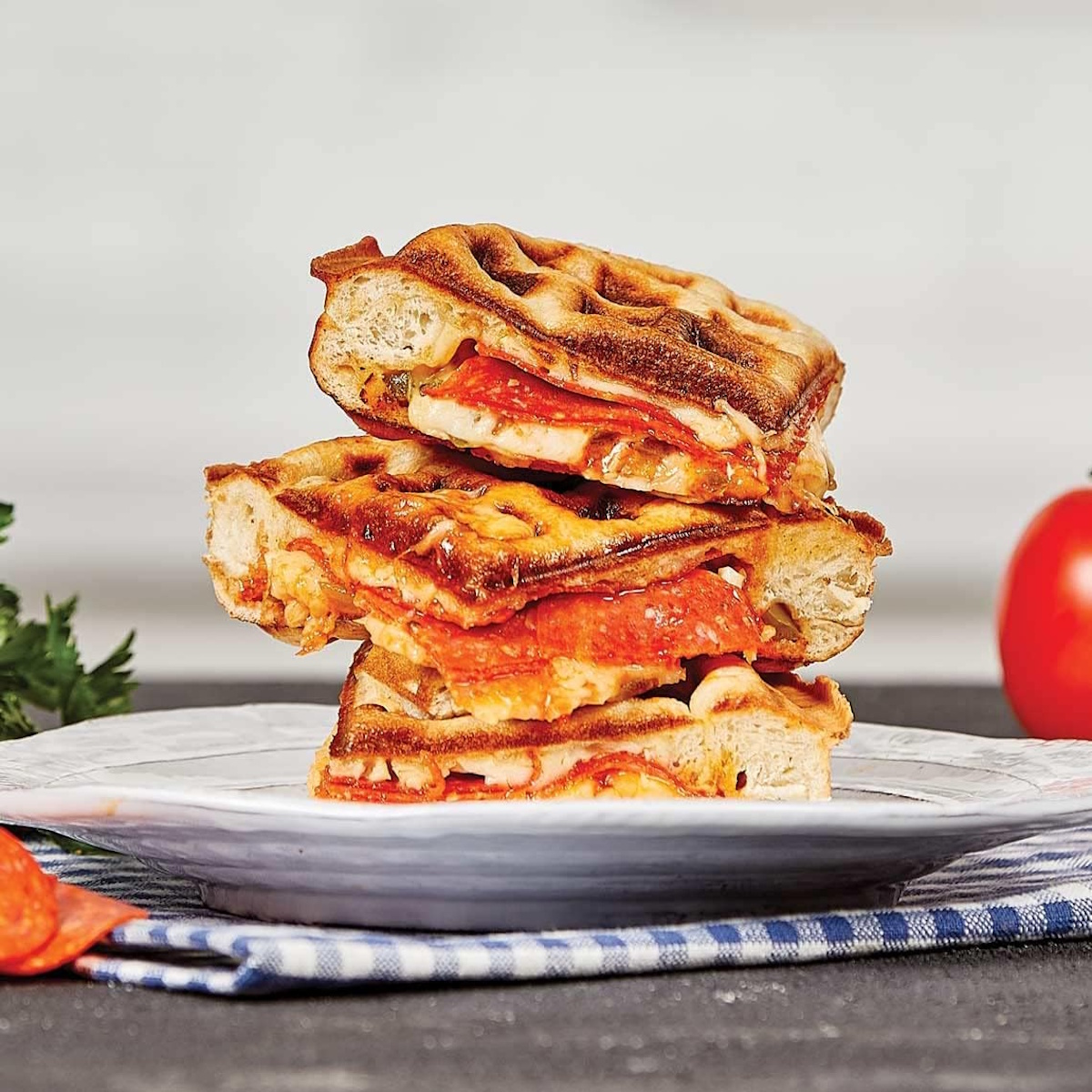 Gestapelte Waffelpizza mit Peperoni und Käse auf einem Teller.