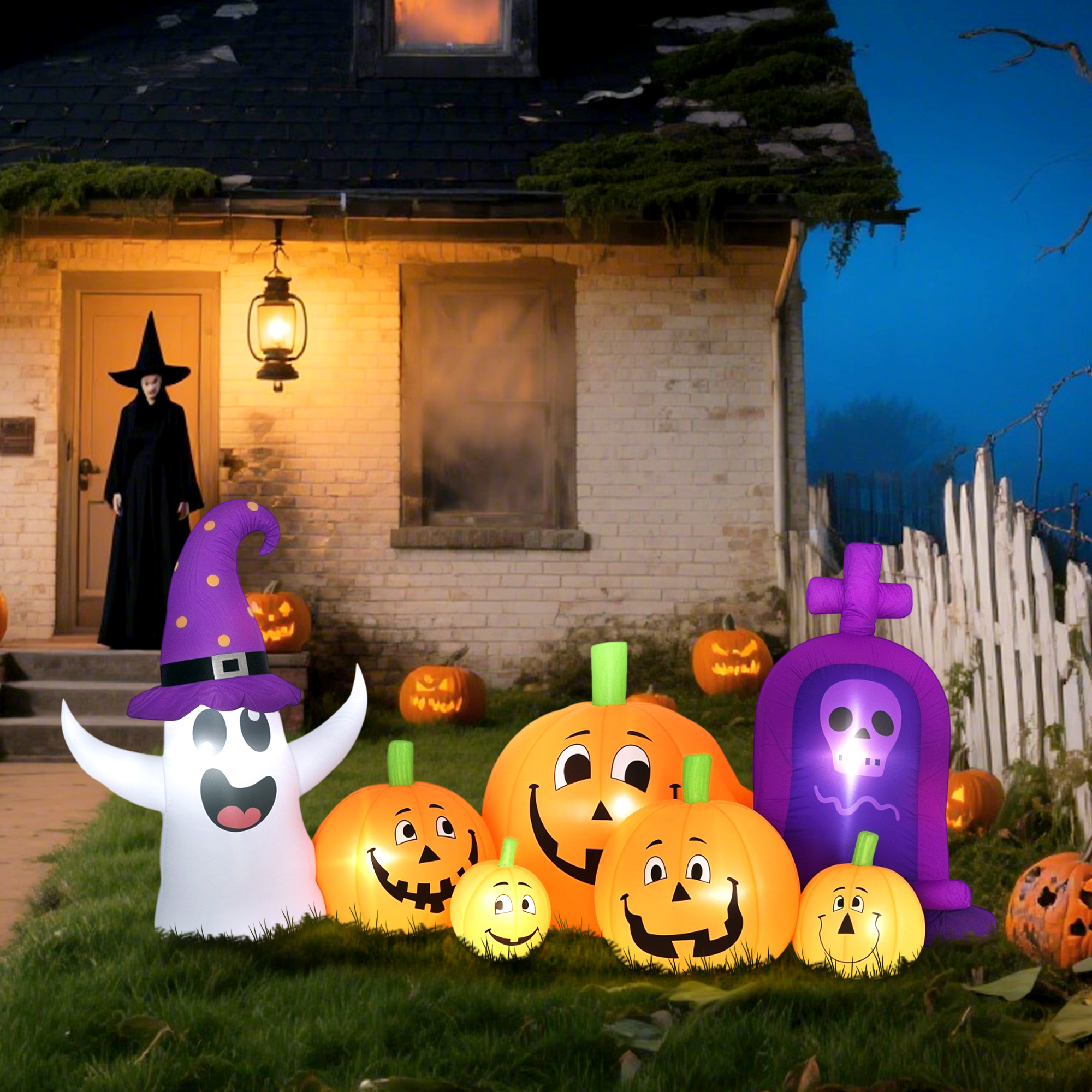 Fantasma inflable, calabazas y lápida frente a una casa con una bruja.