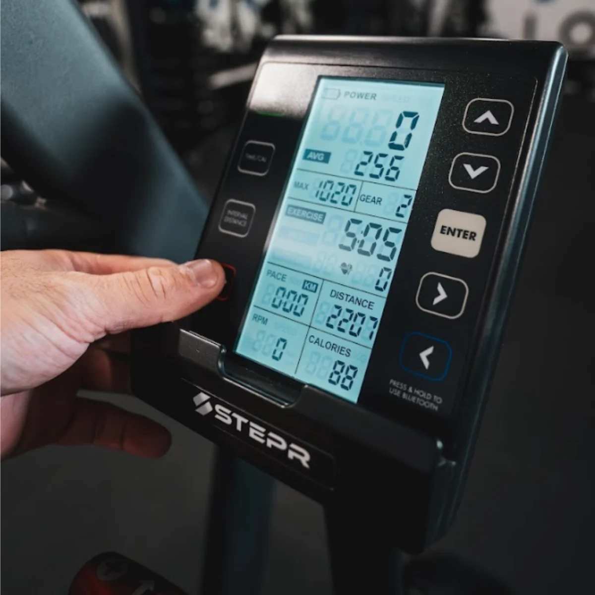 Een man drukt op een rode knop op het display van een fitnessapparaat met trainingsgegevens.