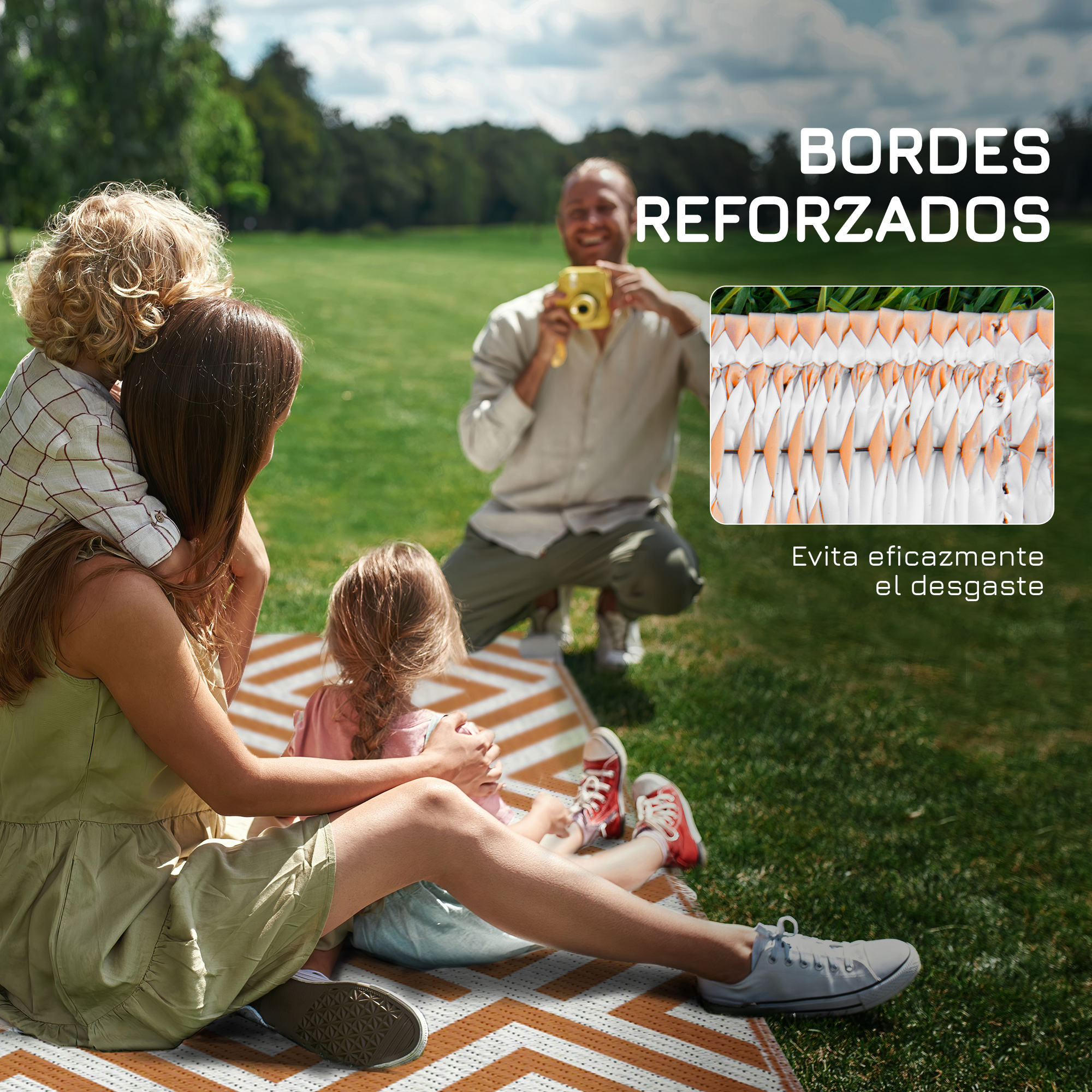 Familia en manta de picnic en el césped, padre toma foto a niños.