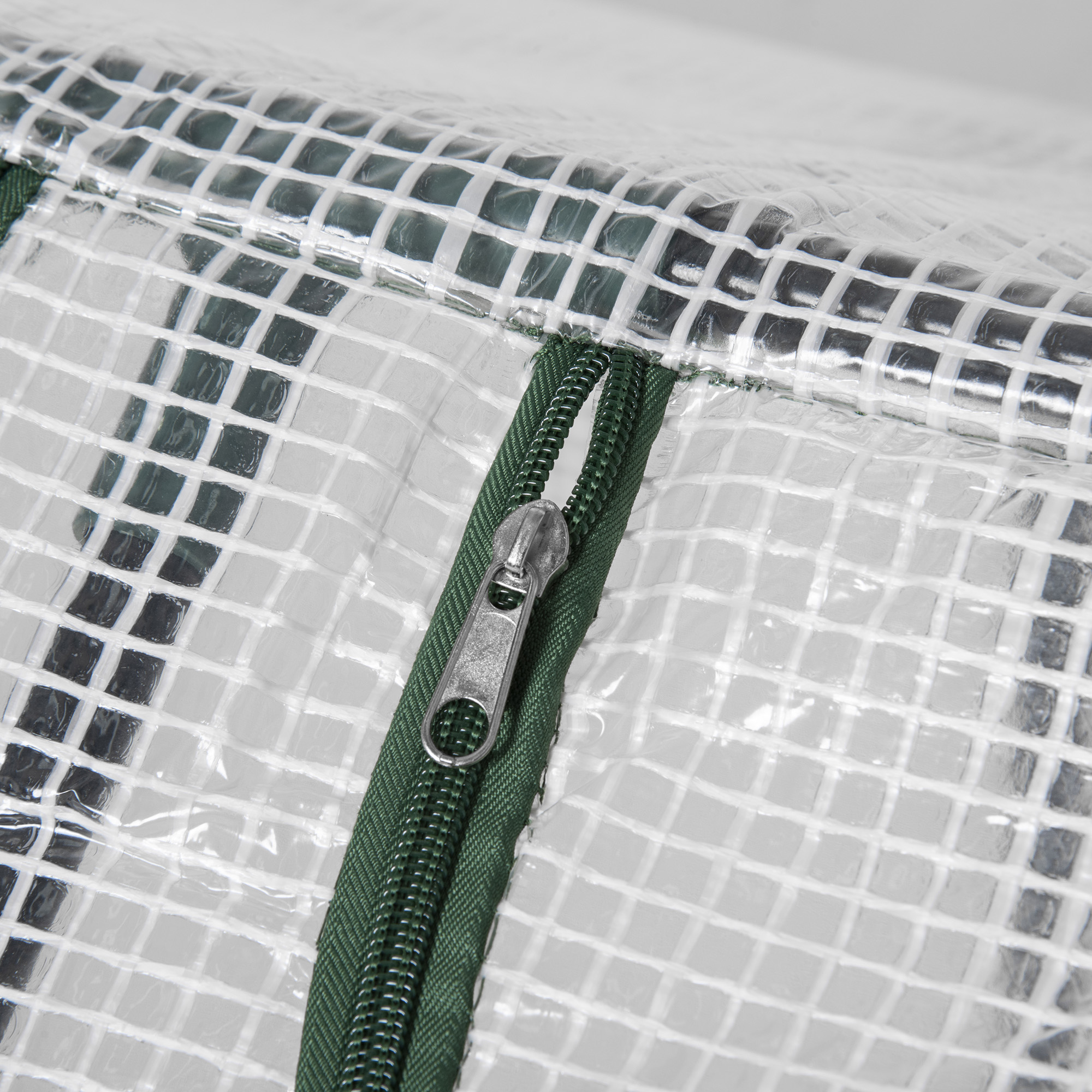 Primer plano de material transparente con cremallera verde y tirador plateado.