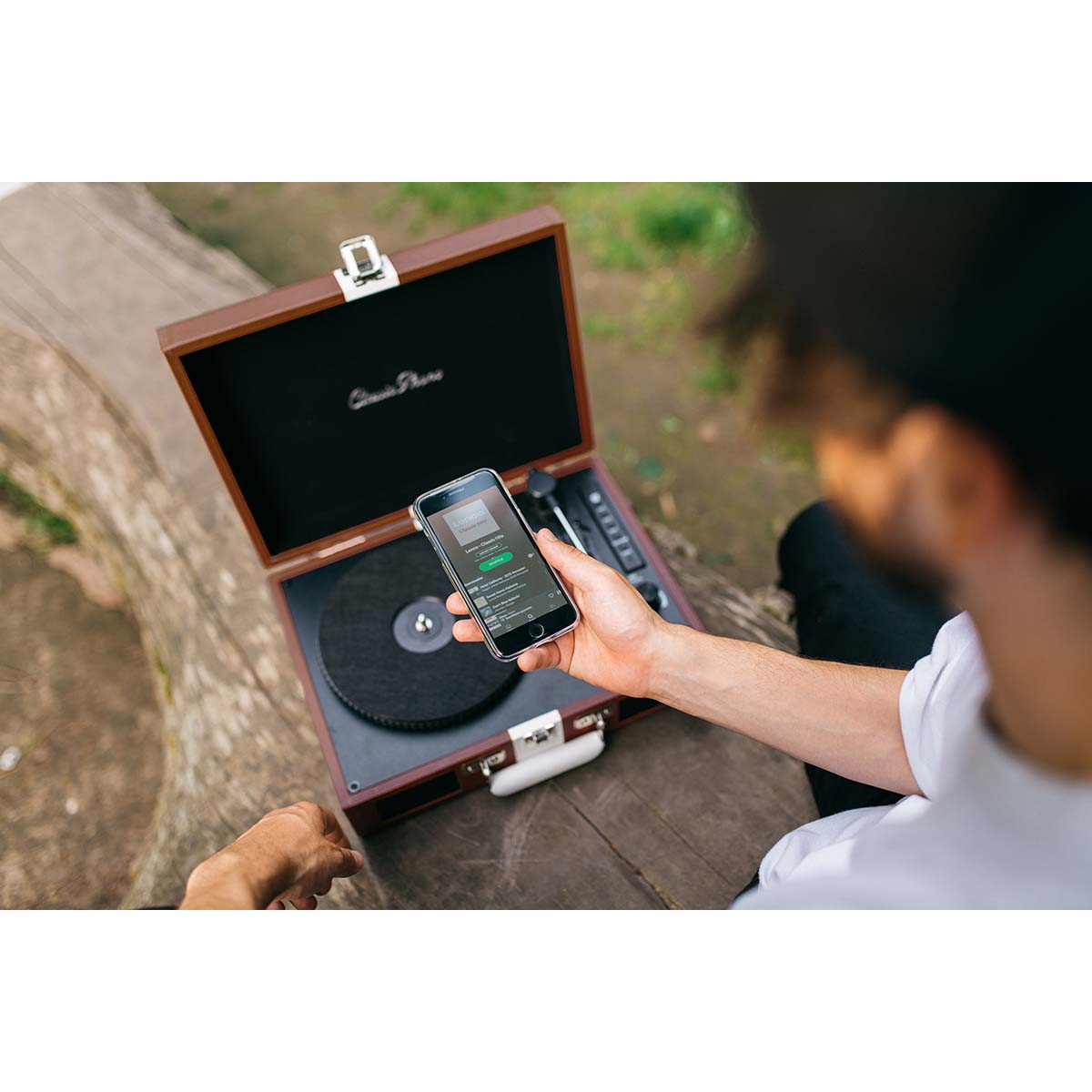 Mężczyzna trzyma smartfon przed gramofonem na zewnątrz