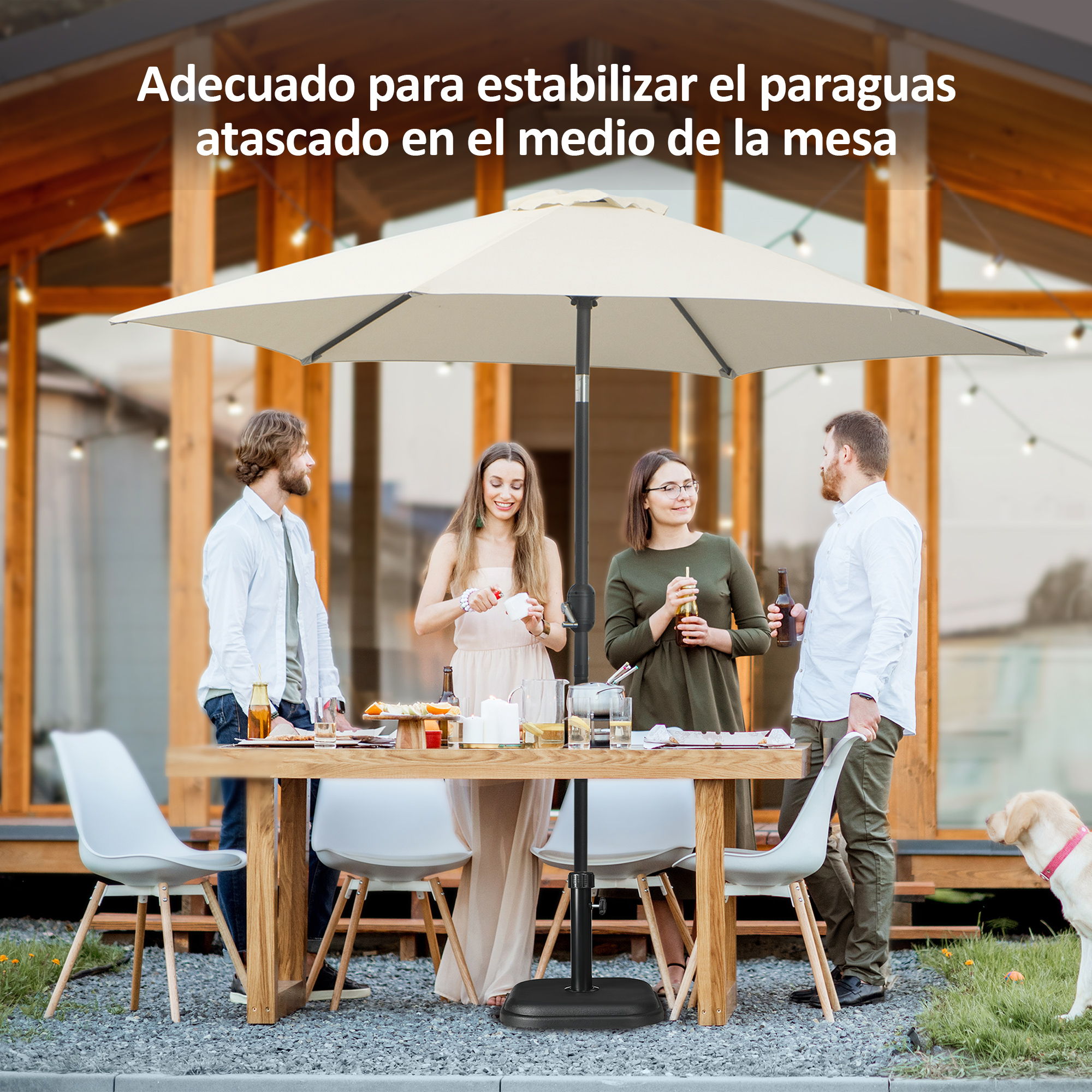 Cuatro personas y un perro se sientan en una mesa de madera bajo una sombrilla exterior.