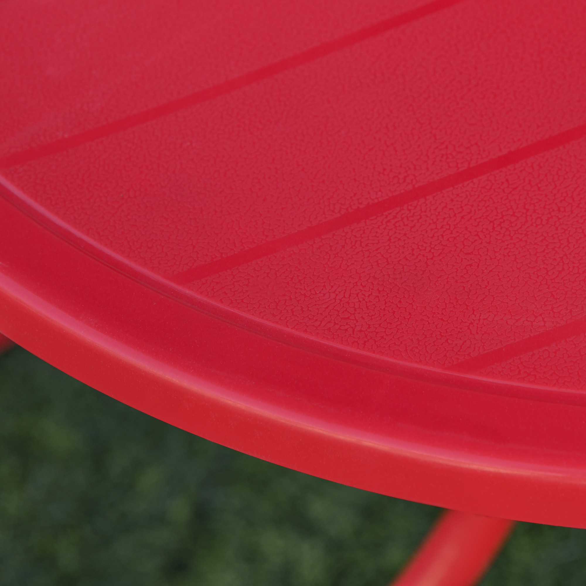 Mesa roja con ranuras y superficie texturizada, sobre césped verde.