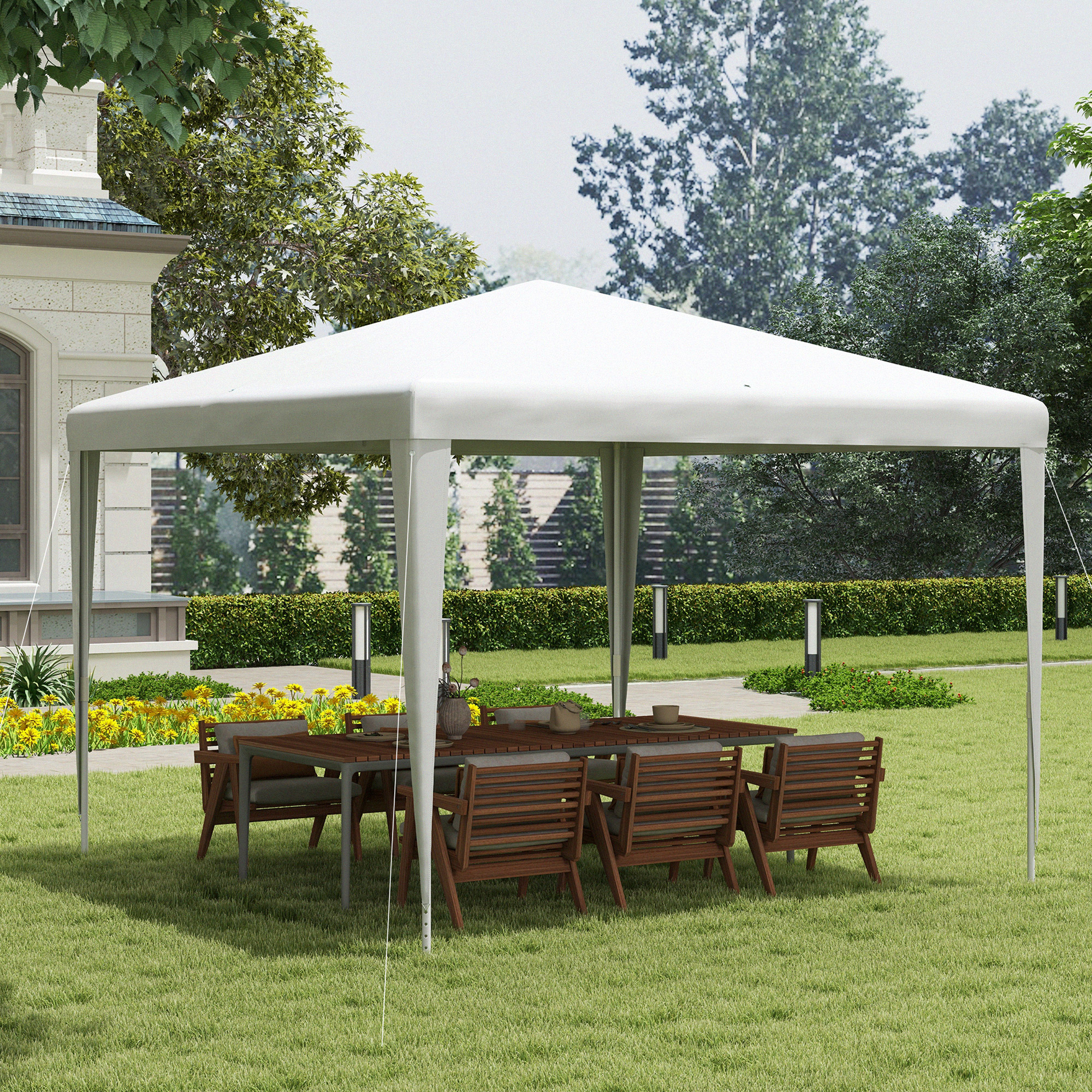 Una tenda bianca con tavolo in legno e sedie in un giardino, circondata da alberi e fiori.