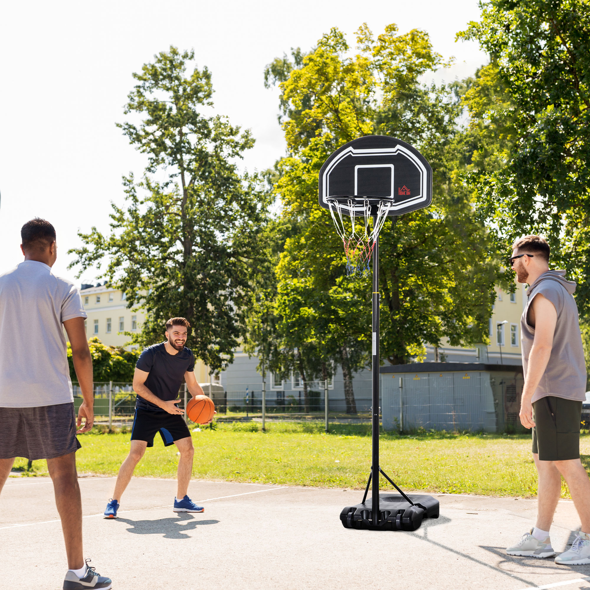 Hombres jugando al baloncesto en una cancha exterior con aro portátil.