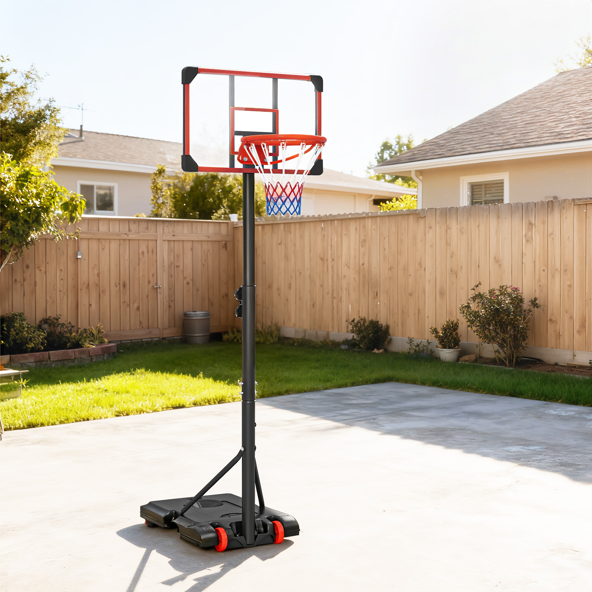 Una canasta de baloncesto portátil con tablero transparente y borde rojo está sobre un patio de concreto.