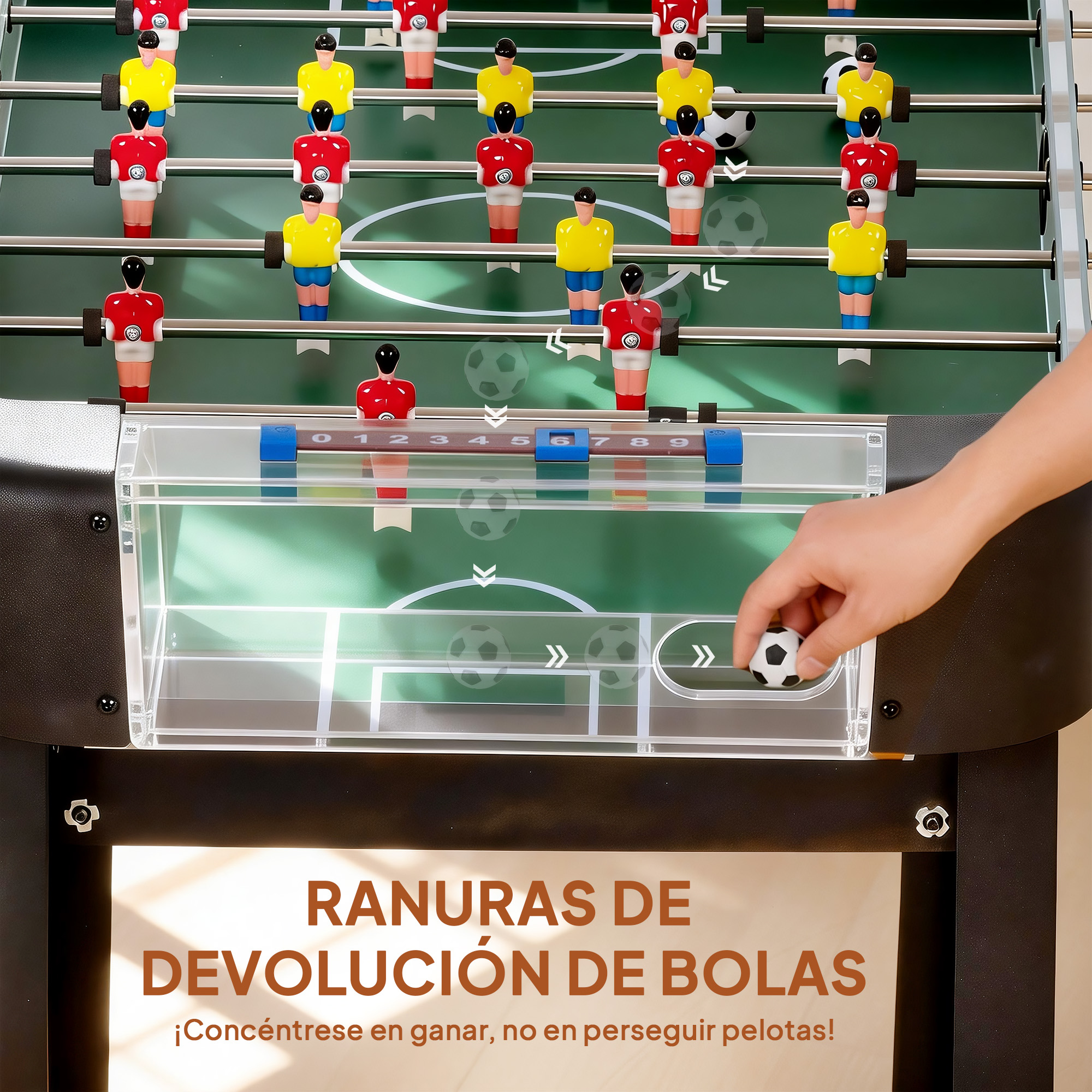 Mesa de futbolín con figuras rojas y amarillas, una mano sostiene una pelota.