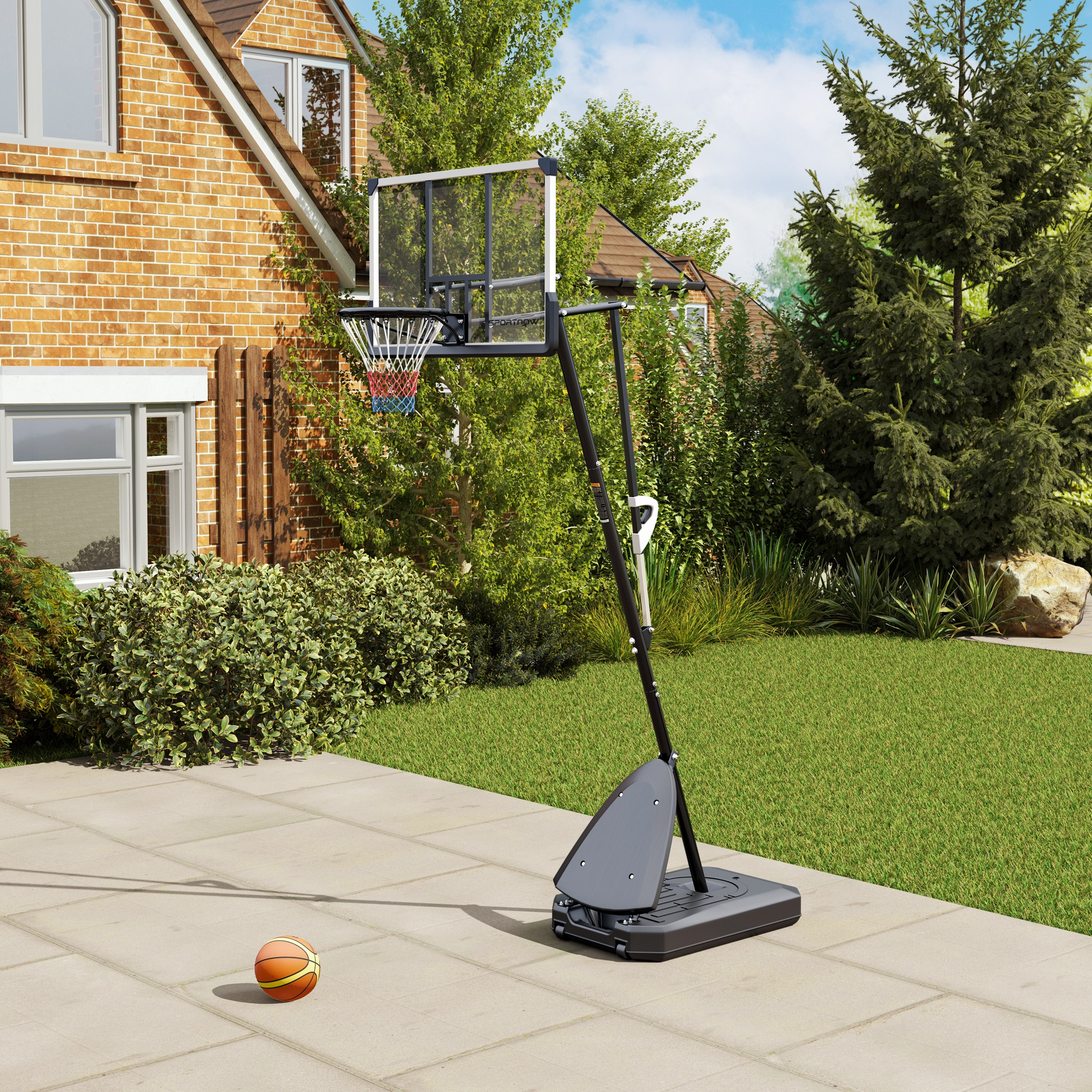 Una canasta de baloncesto está en un patio pavimentado junto a una casa de ladrillos.