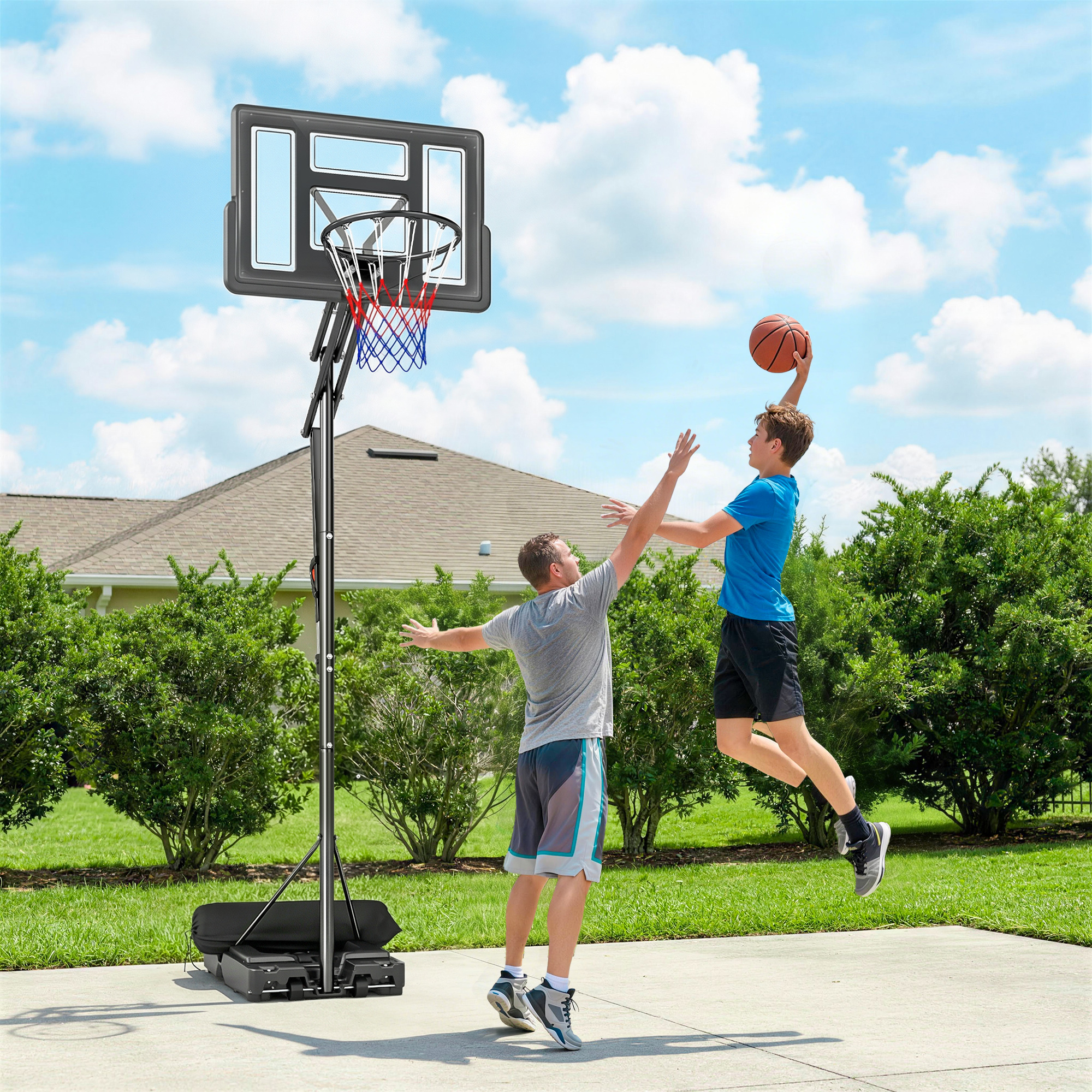 Dos personas juegan al baloncesto en una cancha con un aro portátil.