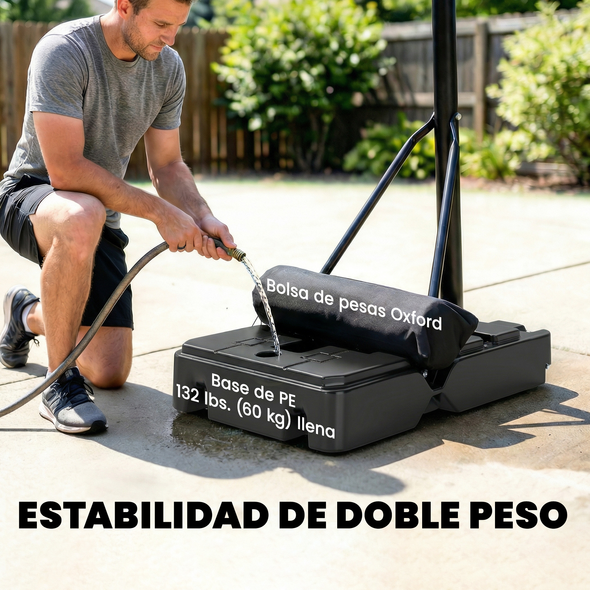 Un hombre llena una base de peso negra con agua de una manguera para un sistema de baloncesto.