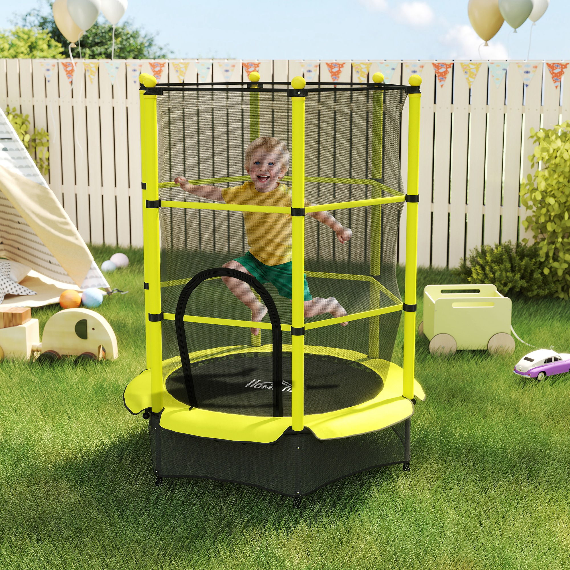 Un niño feliz salta en un trampolín amarillo en el jardín, con juguetes y globos.
