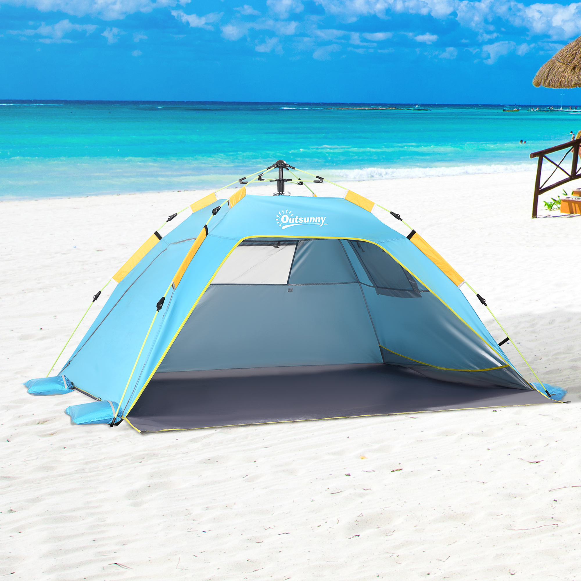 Una carpa de playa azul y amarilla está montada en una playa de arena blanca con agua turquesa.