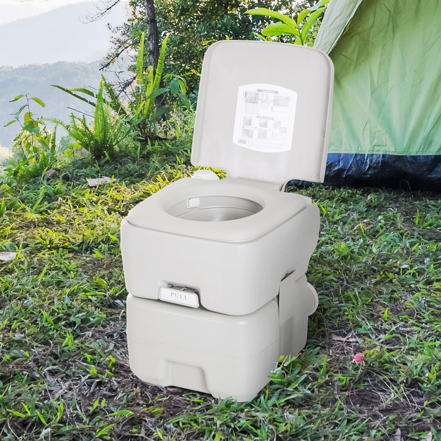 Inodoro portátil junto a una tienda verde en el bosque, con montañas de fondo.