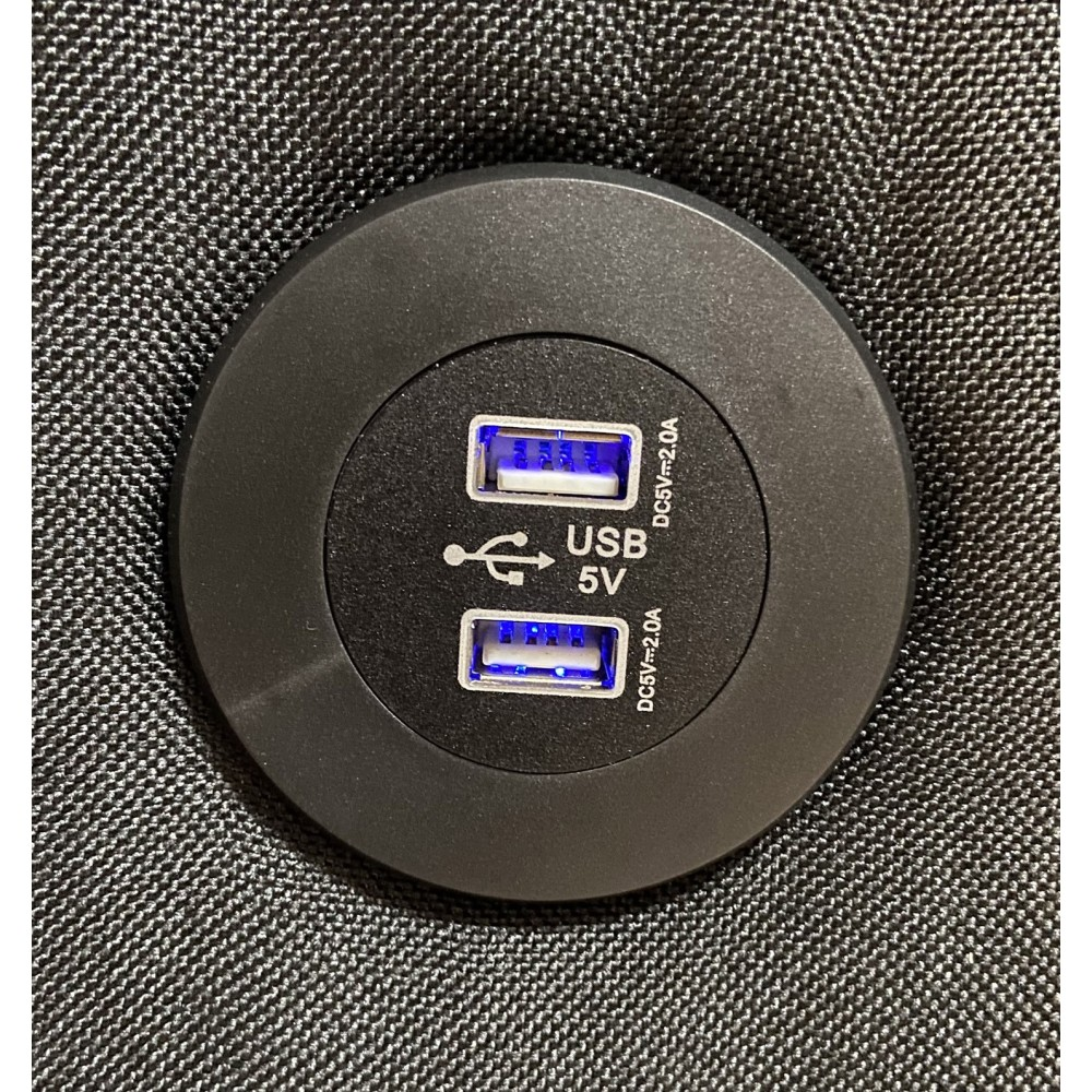 Un puerto USB redondo negro con dos puertos USB azules y etiquetado.