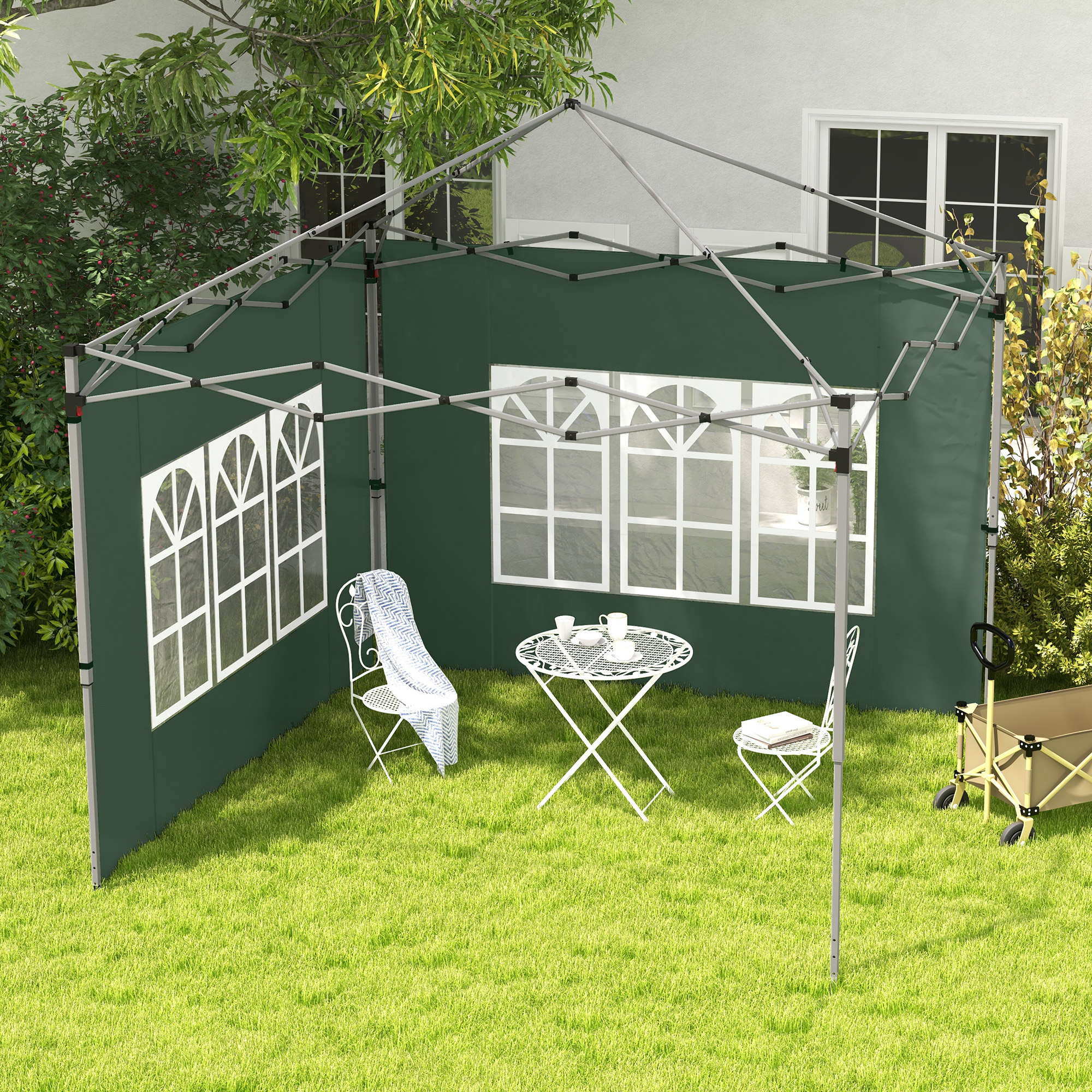 Gazebo verde con ventanas en un jardín, con mesa y sillas blancas.