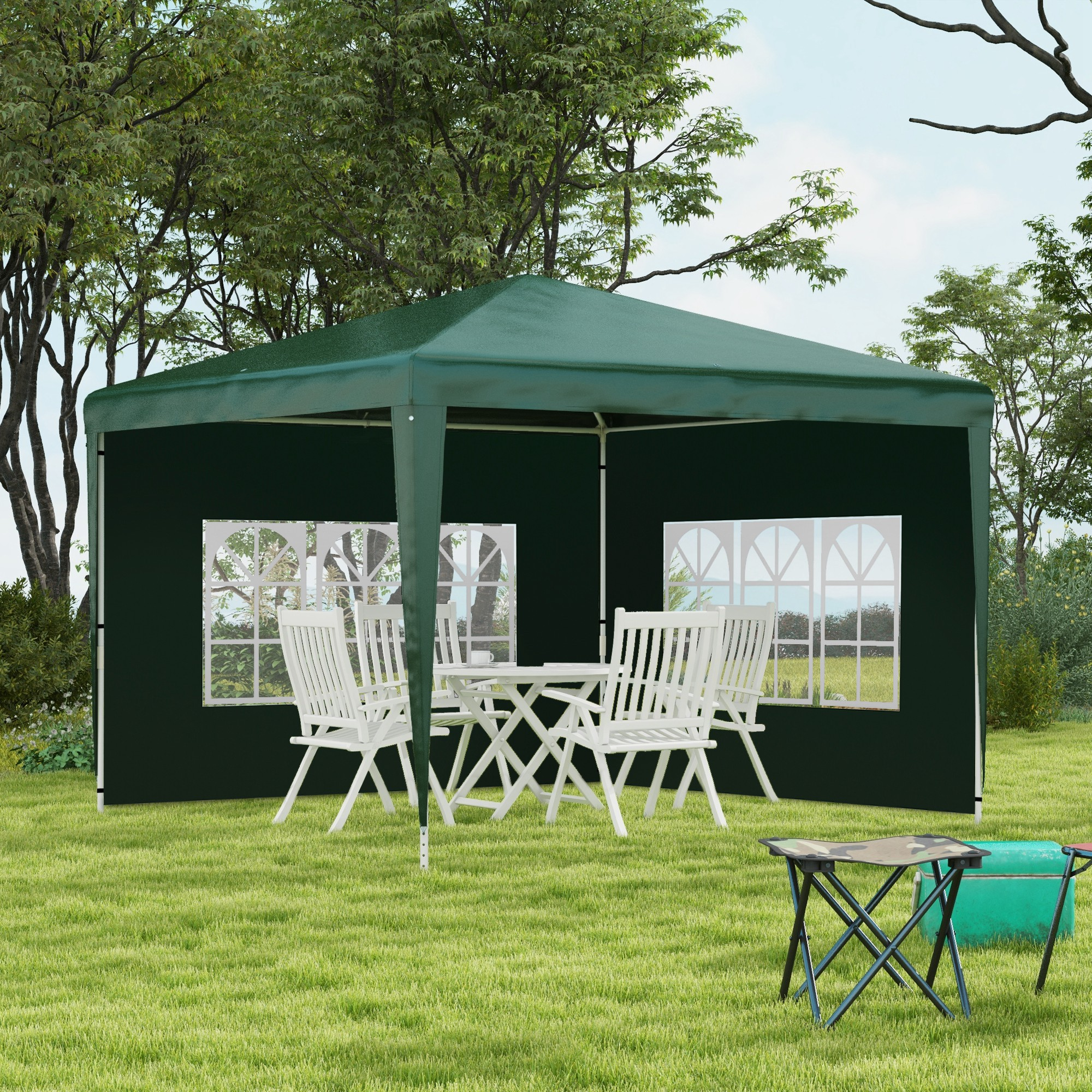 Una carpa verde con mesas y sillas se asienta sobre un césped.