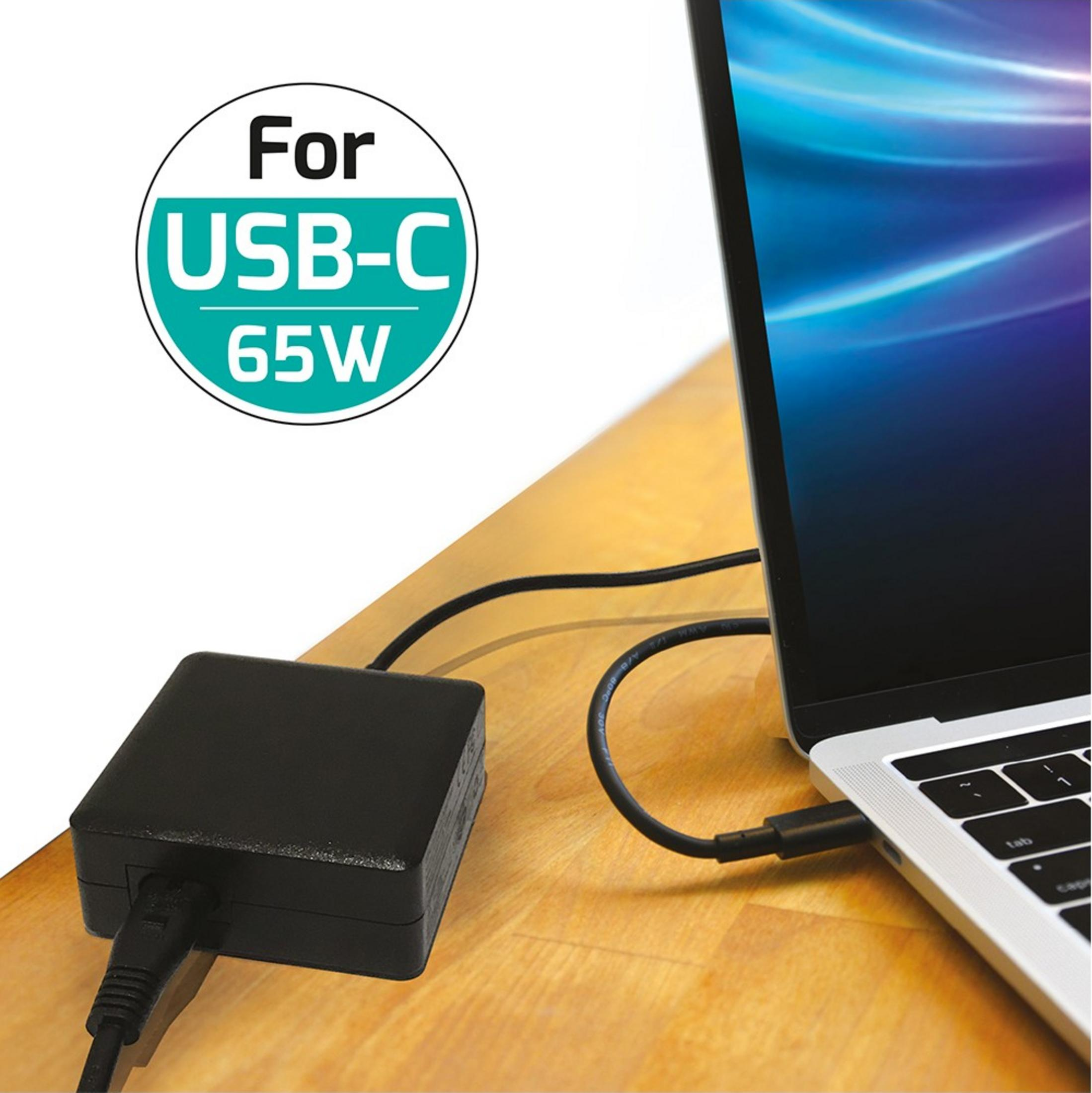 Un caricatore USB-C da 65W nero collegato a un laptop argentato su una scrivania di legno.