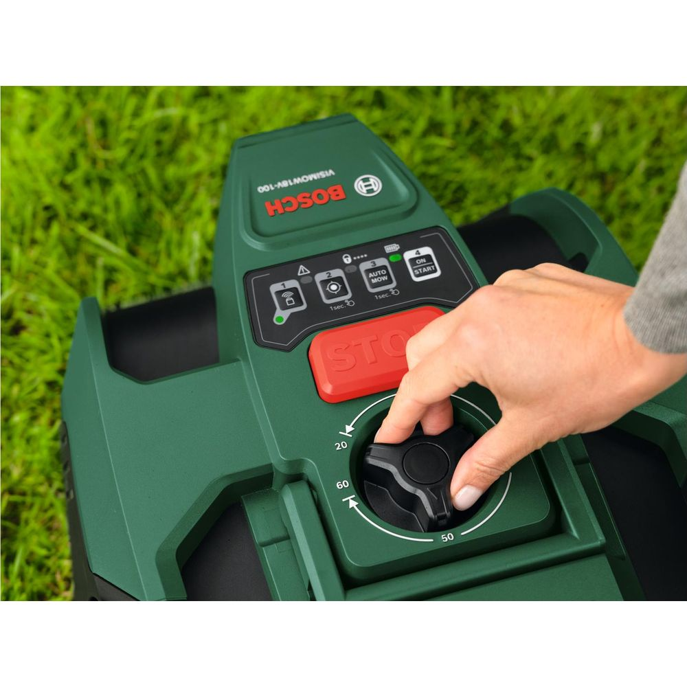 Una mano regola una manopola su un tosaerba robot Bosch verde sull'erba.