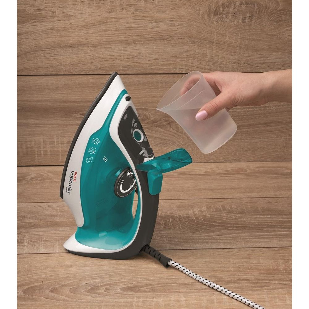 Eine Hand gießt Wasser aus einem Messbecher in ein Bügeleisen.