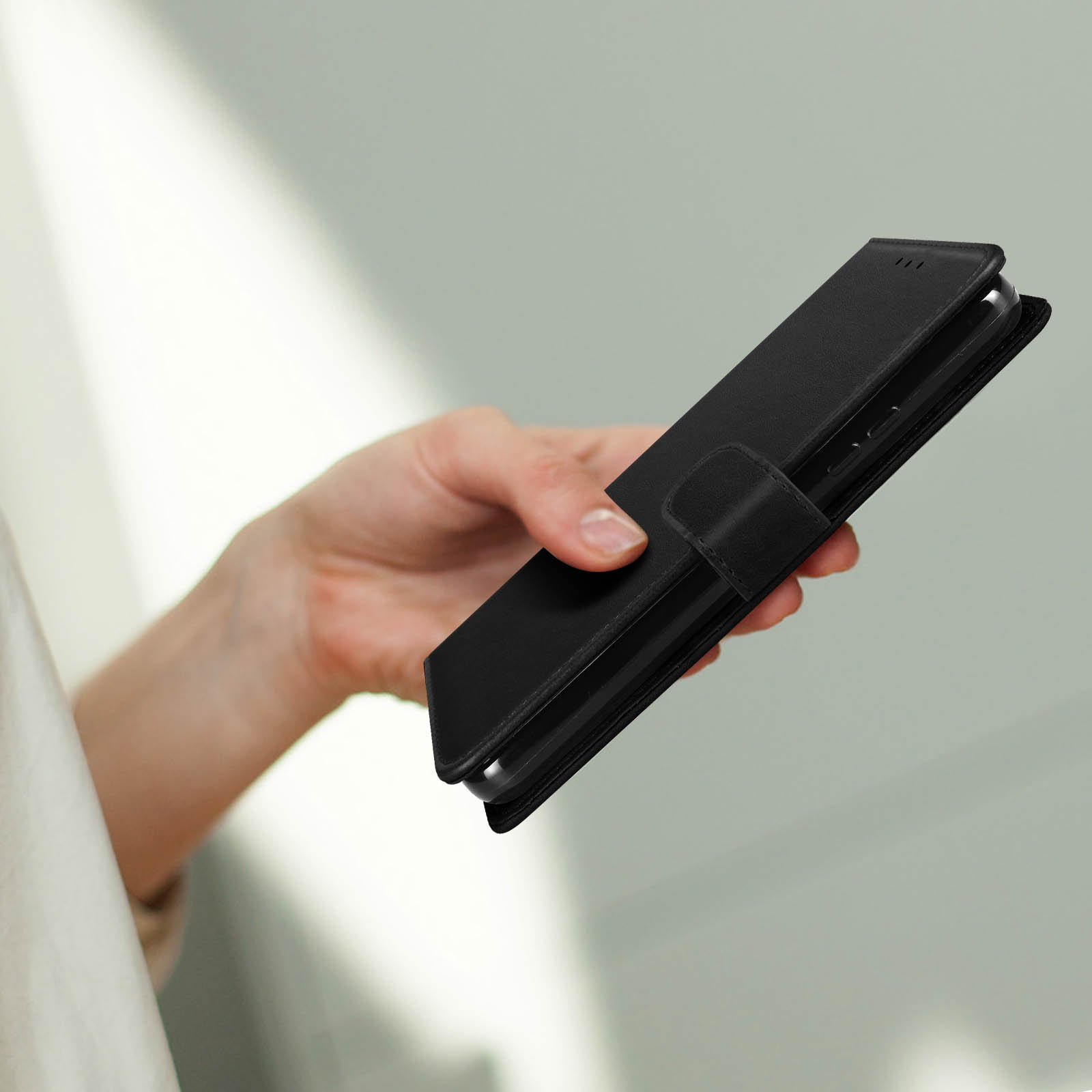 Eine Hand hält ein schwarzes Handy mit einer Schutzhülle.