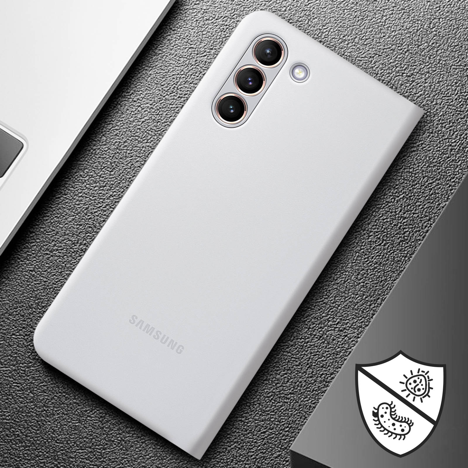 Un smartphone blanco sobre una superficie texturizada junto a un portátil. Incluye icono de escudo.