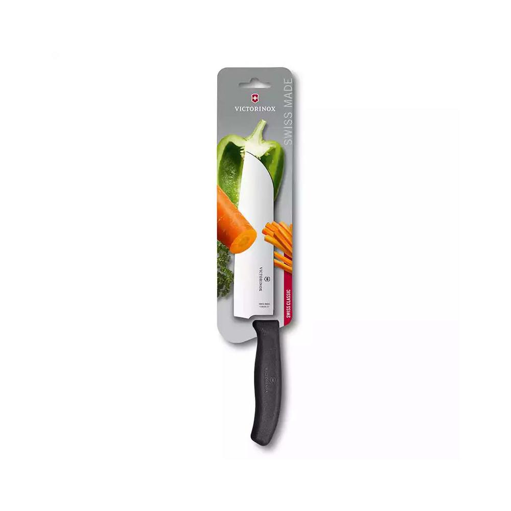 Un cuchillo Victorinox con mango negro, empaquetado con zanahorias y pimiento verde.