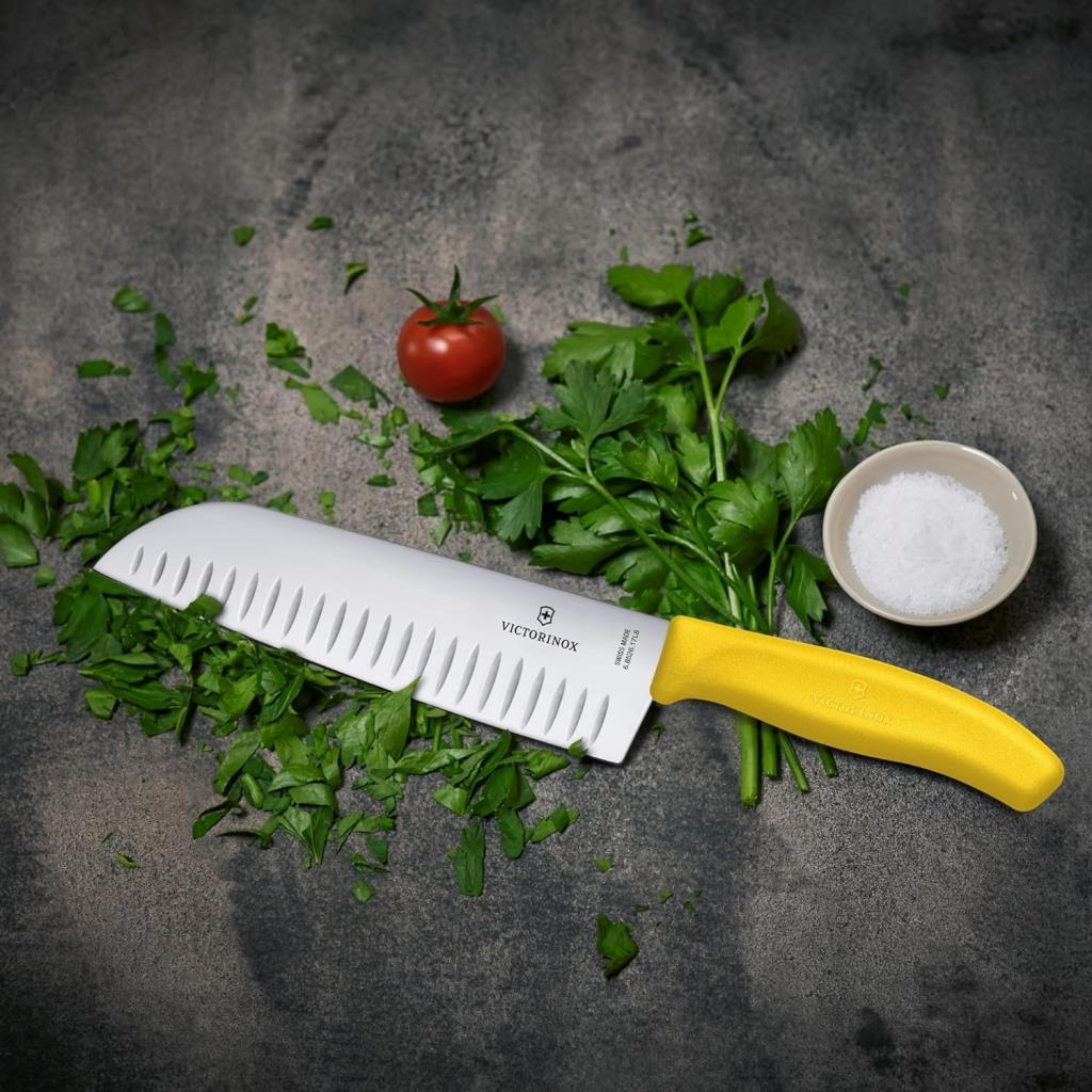 Sarı saplı beyaz bir Victorinox bıçağı maydanozun üzerinde duruyor.