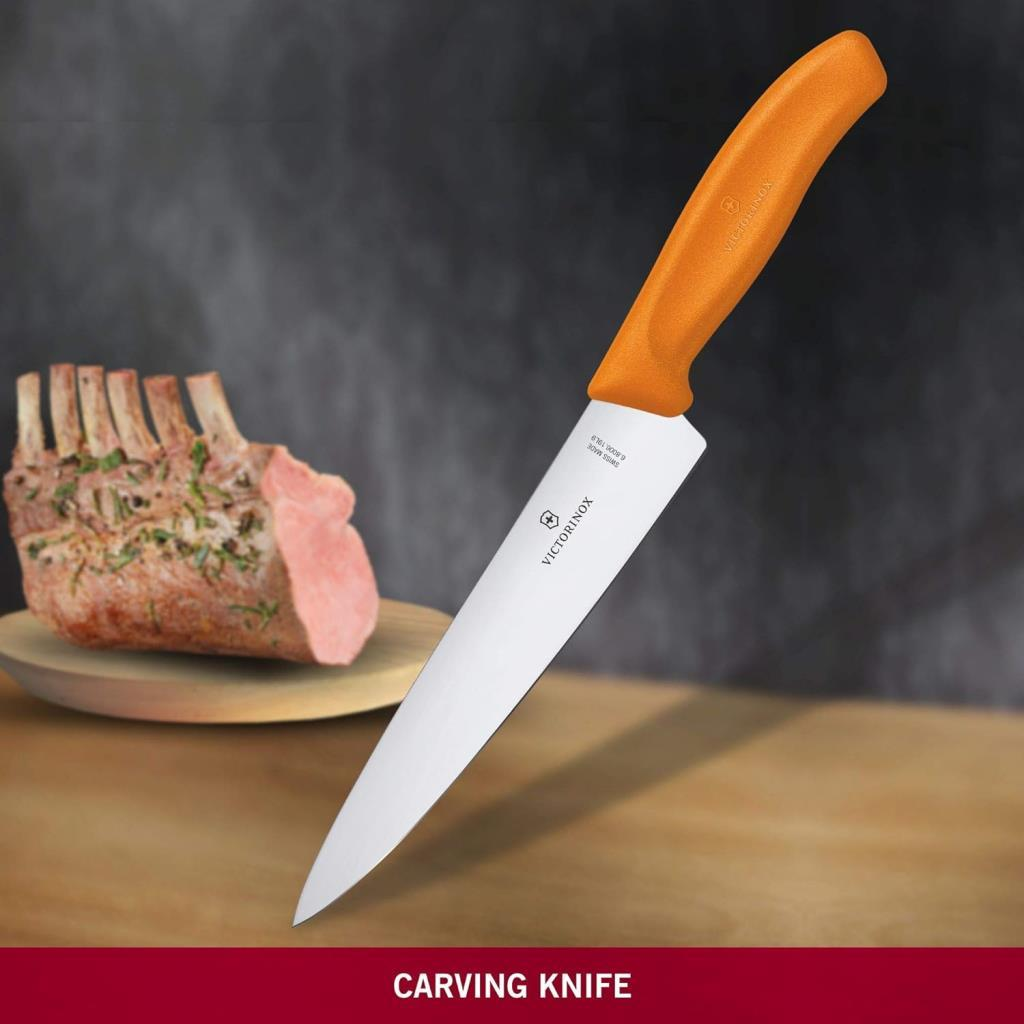 Ahşap bir tabakta çiğ pirzola yanında turuncu Victorinox bıçağı.