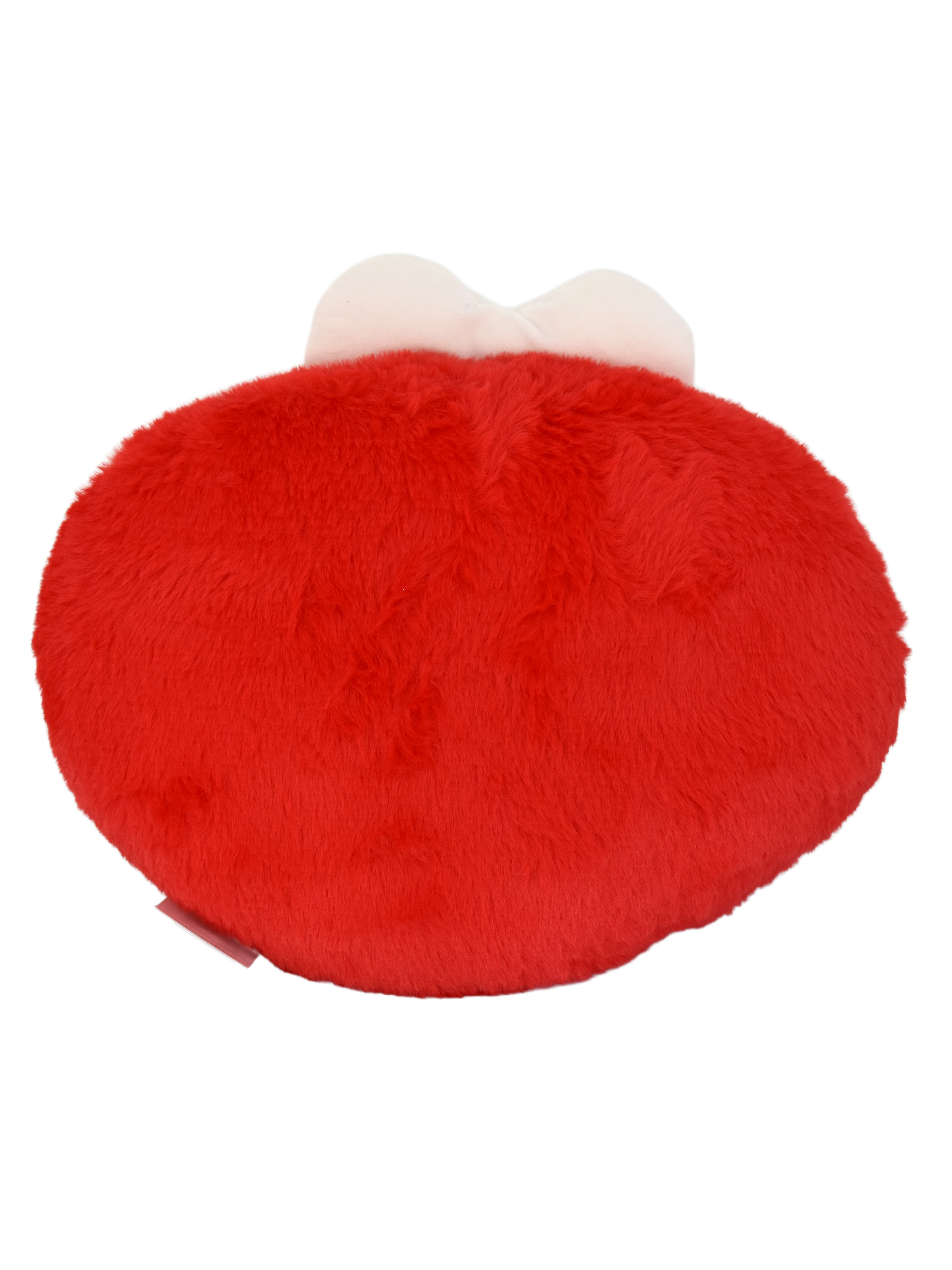 Ein rotes, flauschiges Kissen in Herzform mit einer weißen Schleife oben.