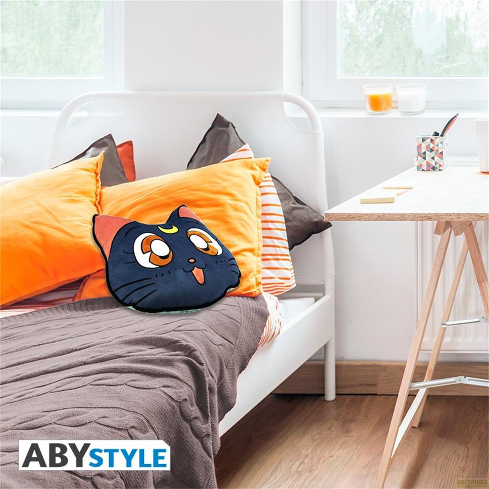 Ein dunkelblauer Katzenkissen mit Mond-Symbol liegt auf einem Bett mit orangefarbenen Kissen.
