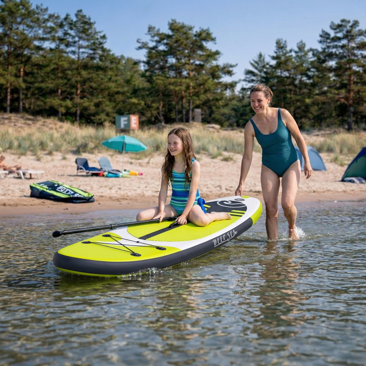 Kobieta i dziewczynka na desce SUP w wodzie przy plaży.