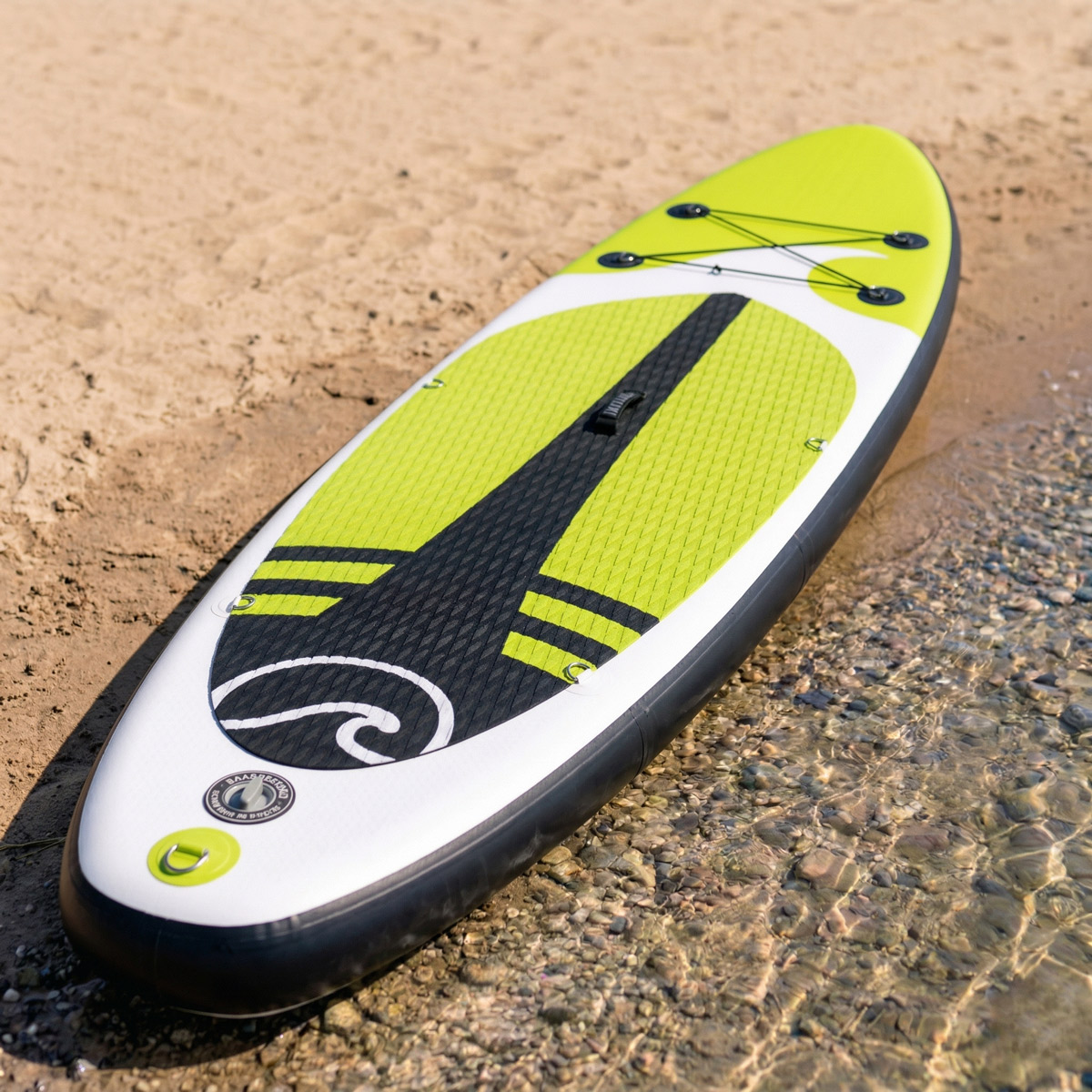 Jasnożółta i biała deska do paddleboardingu leży na piaszczystym brzegu w płytkiej wodzie.