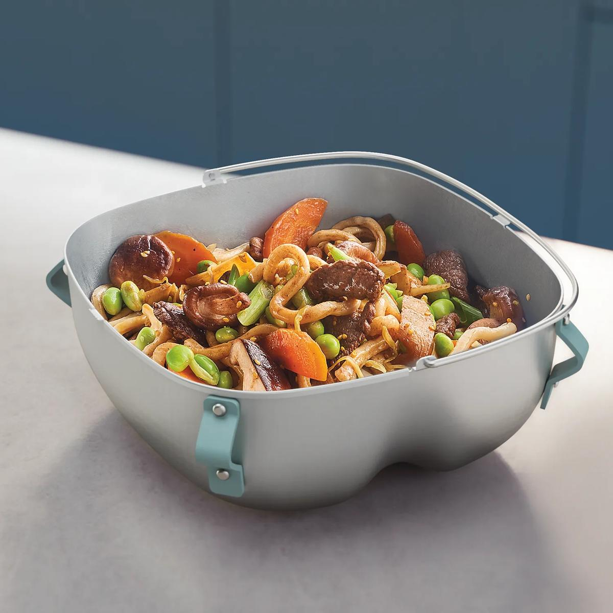 Un contenitore grigio pieno di noodles, carne, funghi, carote ed edamame.