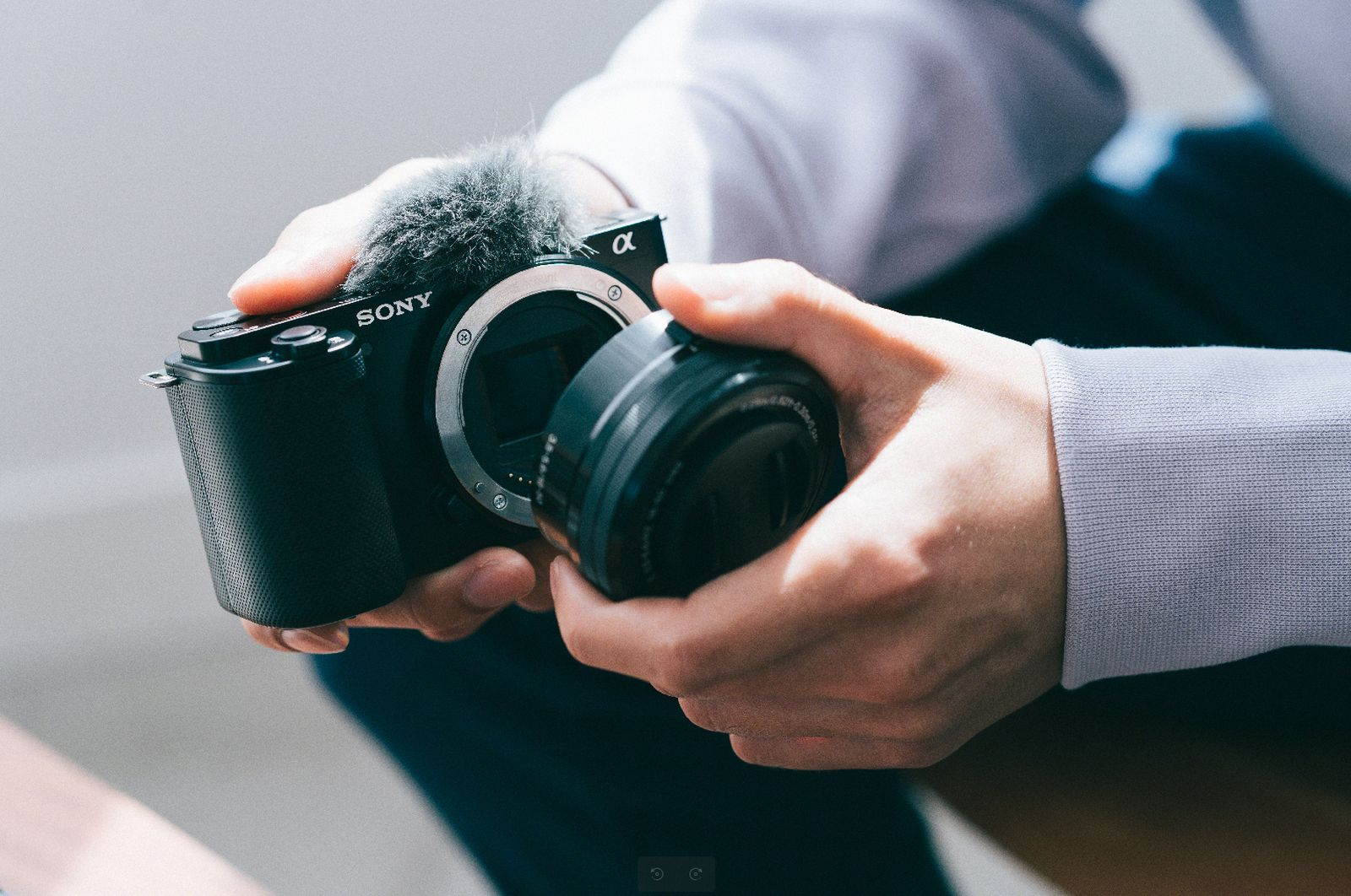 Dłonie wymieniają aparat Sony z podłączonym mikrofonem i obiektywem.