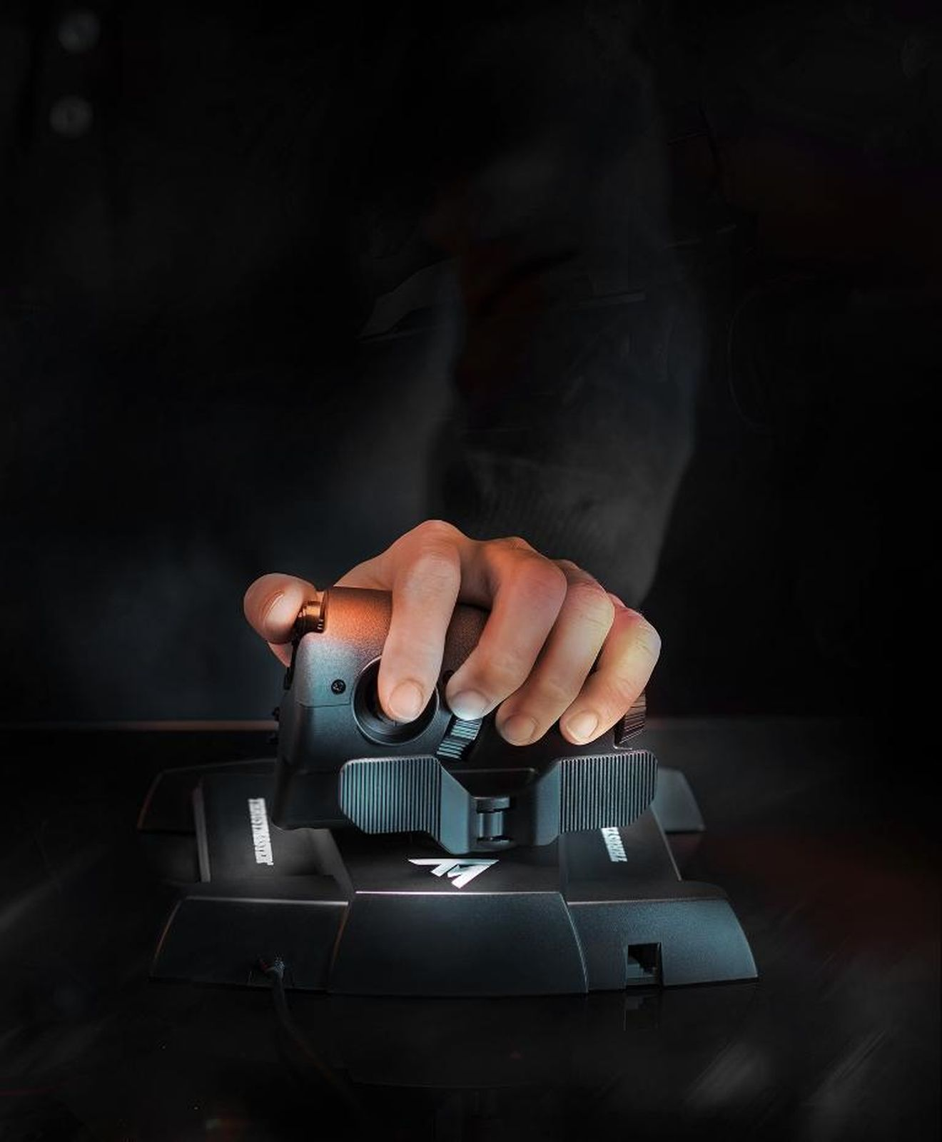 A hand operates a black joystick with buttons against a dark background.
