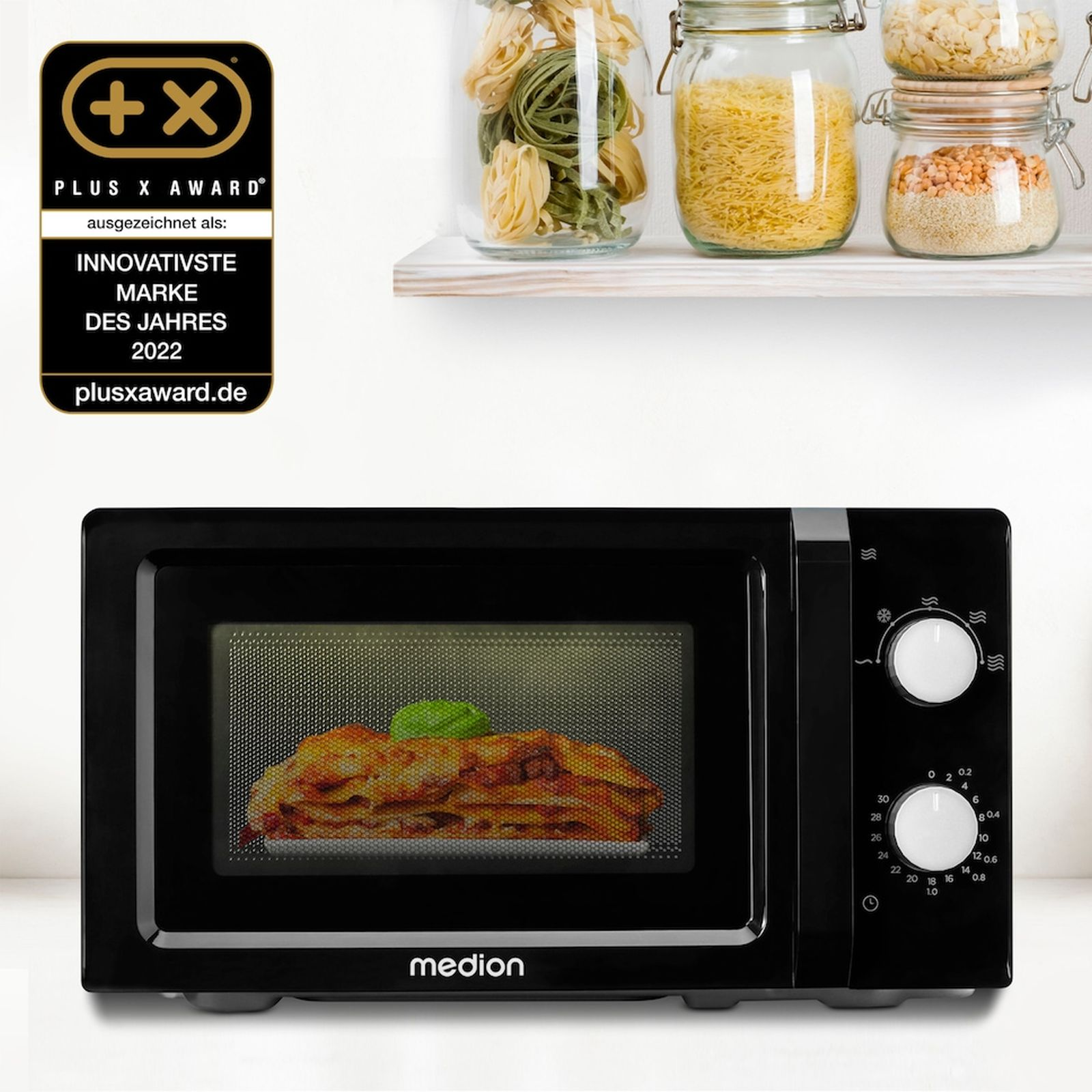 Czarna kuchenka mikrofalowa z lasagne w środku i nagrodą po lewej.