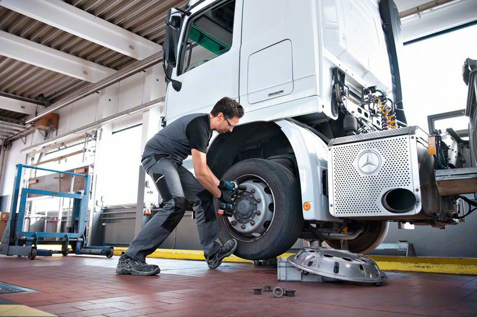 Mechaniker repariert LKW-Rad in Werkstatt mit Werkzeug, detaillierte Ansicht.