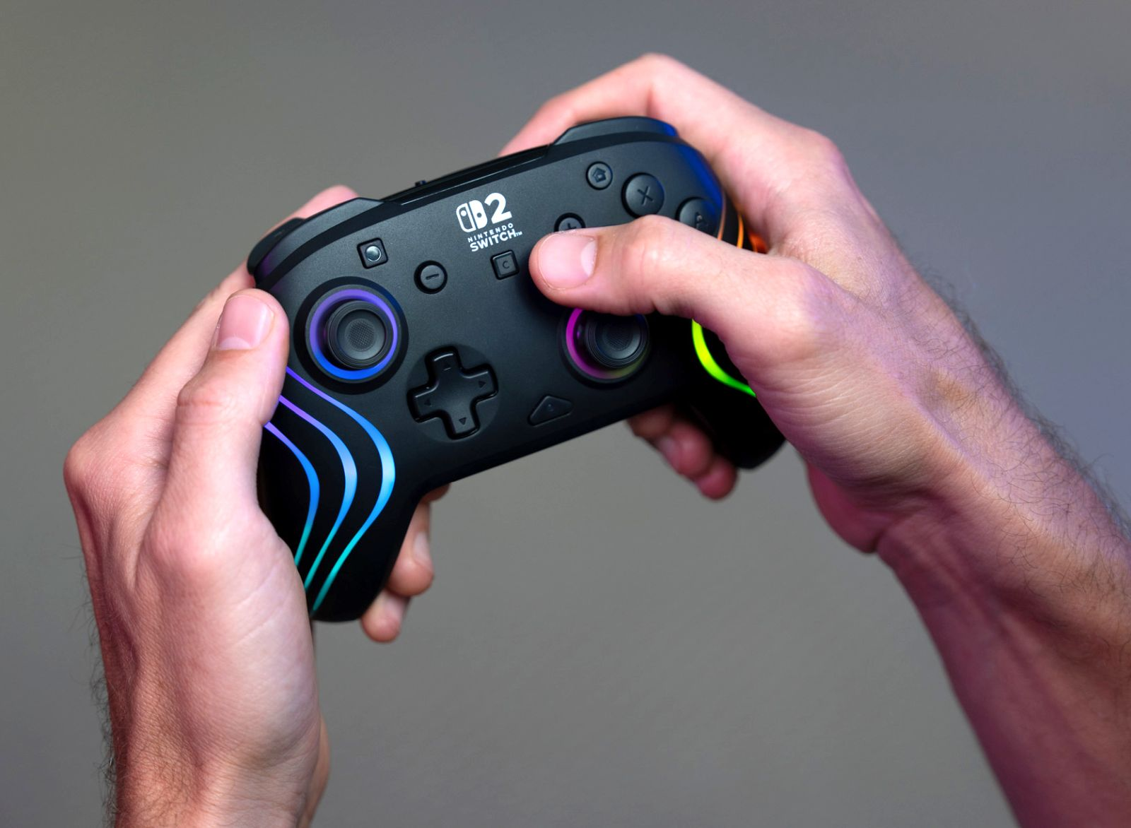 Mani che tengono un controller nero Nintendo Switch con luci colorate.