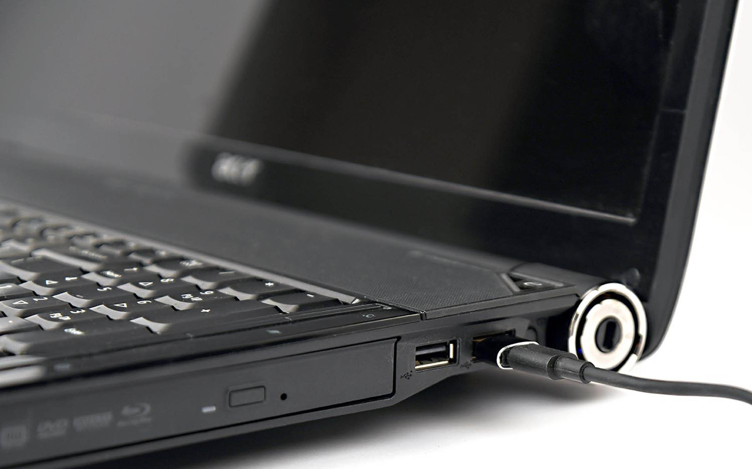 Ein schwarzes Laptop mit einem USB-Kabel, das in den Anschluss gesteckt ist.