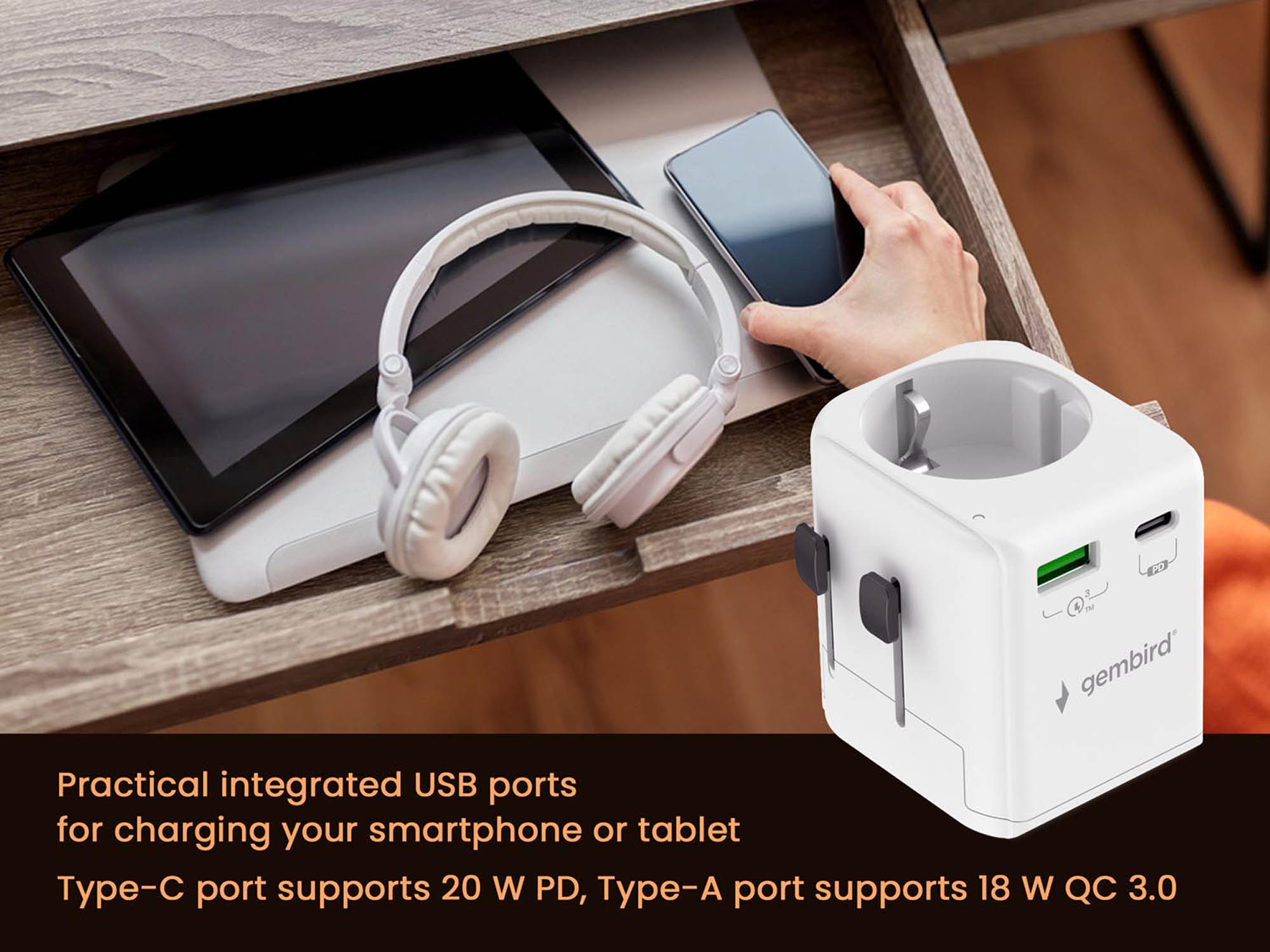 A white travel adapter with USB ports sits beside a tablet, headphones, and a smartphone.