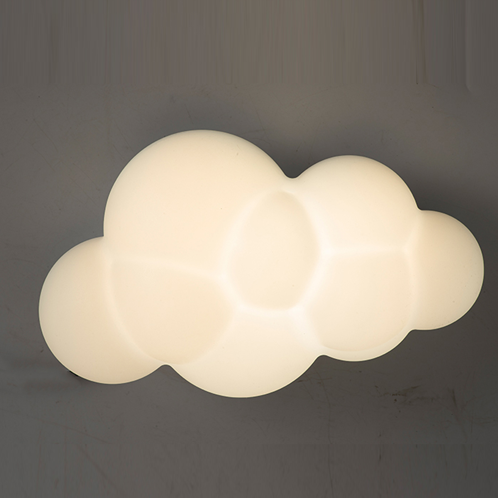 Una lámpara blanca con forma de nube brilla sobre un fondo oscuro.