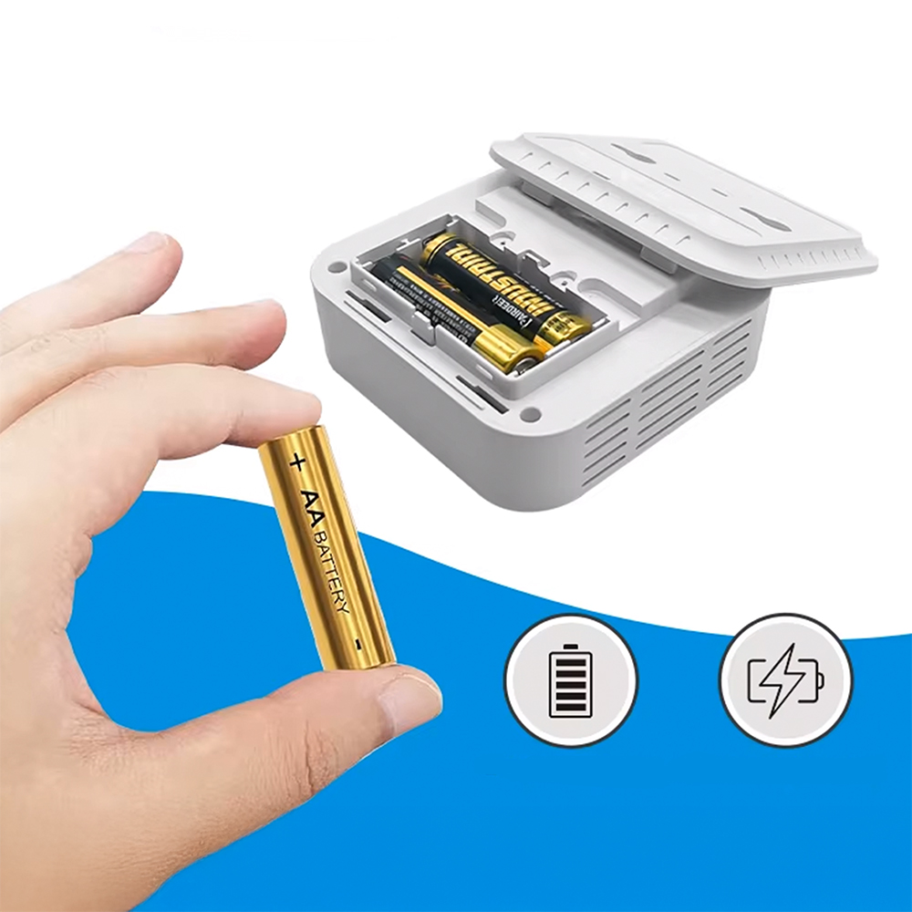 Dłoń trzyma baterię AA obok otwartego pojemnika na baterie z dwoma bateriami.