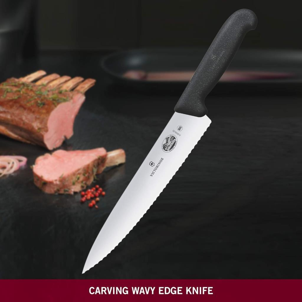 Dalgalı kenarlı Victorinox bıçağı, koyu yüzeyde kavrulmuş etin yanında duruyor.