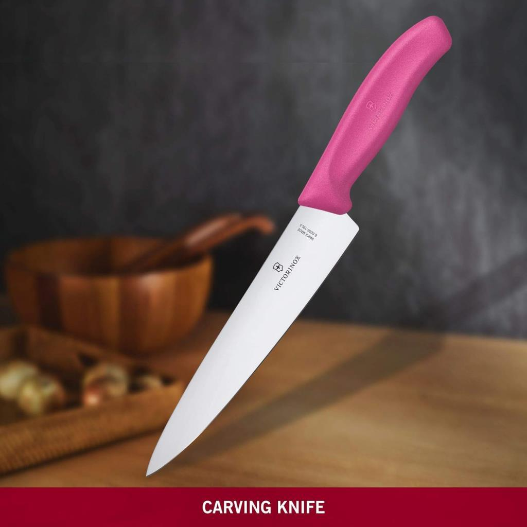 Beyaz bıçaklı pembe Victorinox oyma bıçağı ahşap bir masanın üzerinde duruyor.