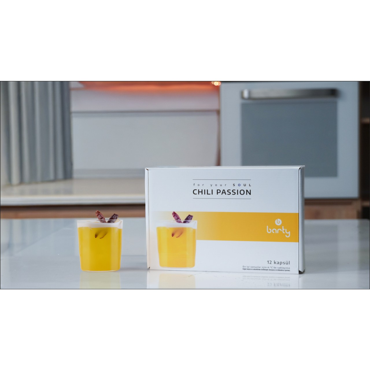 İki bardak sarı içecek ve biber garnitürlü "Chili Passion" kutusu.